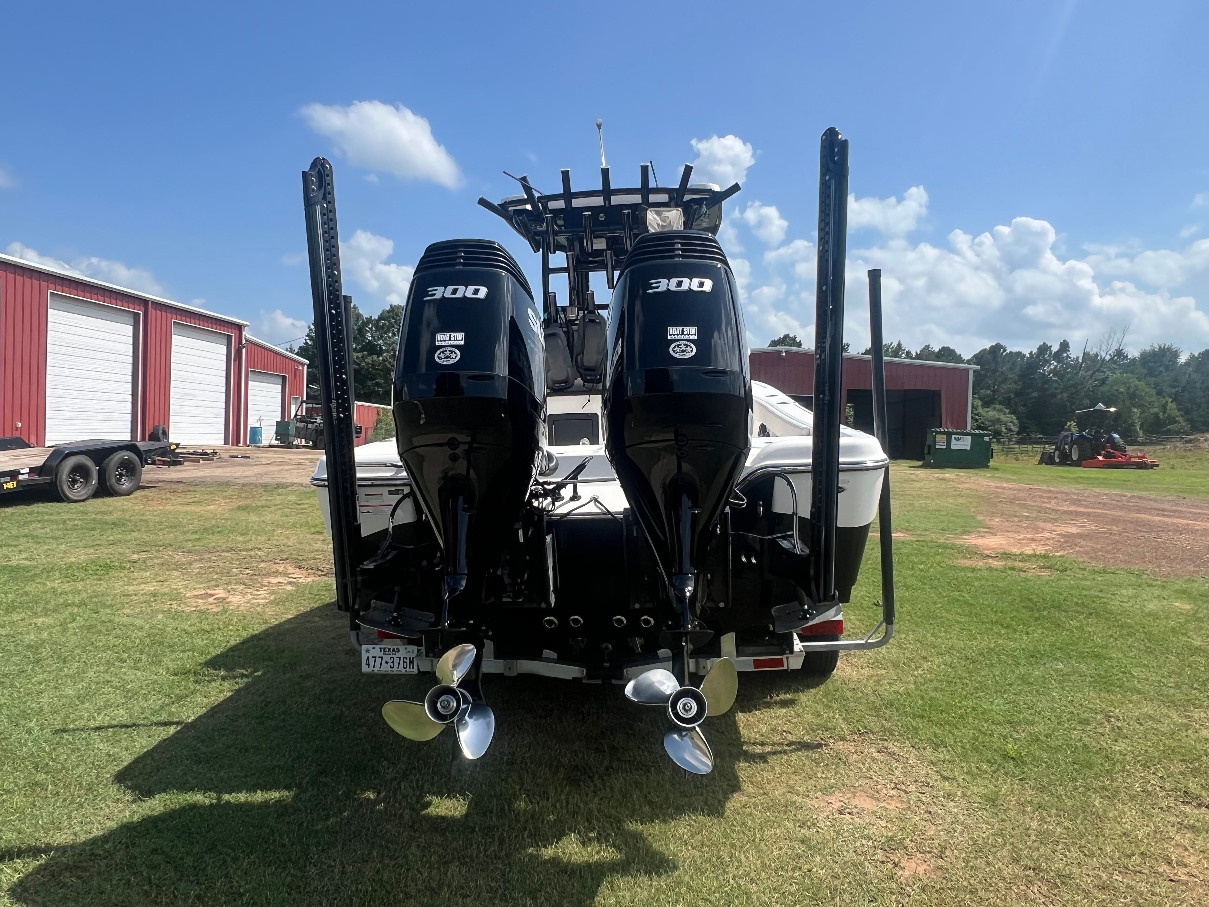 The image shows a boat with two powerful outboard motors on a grassy area.