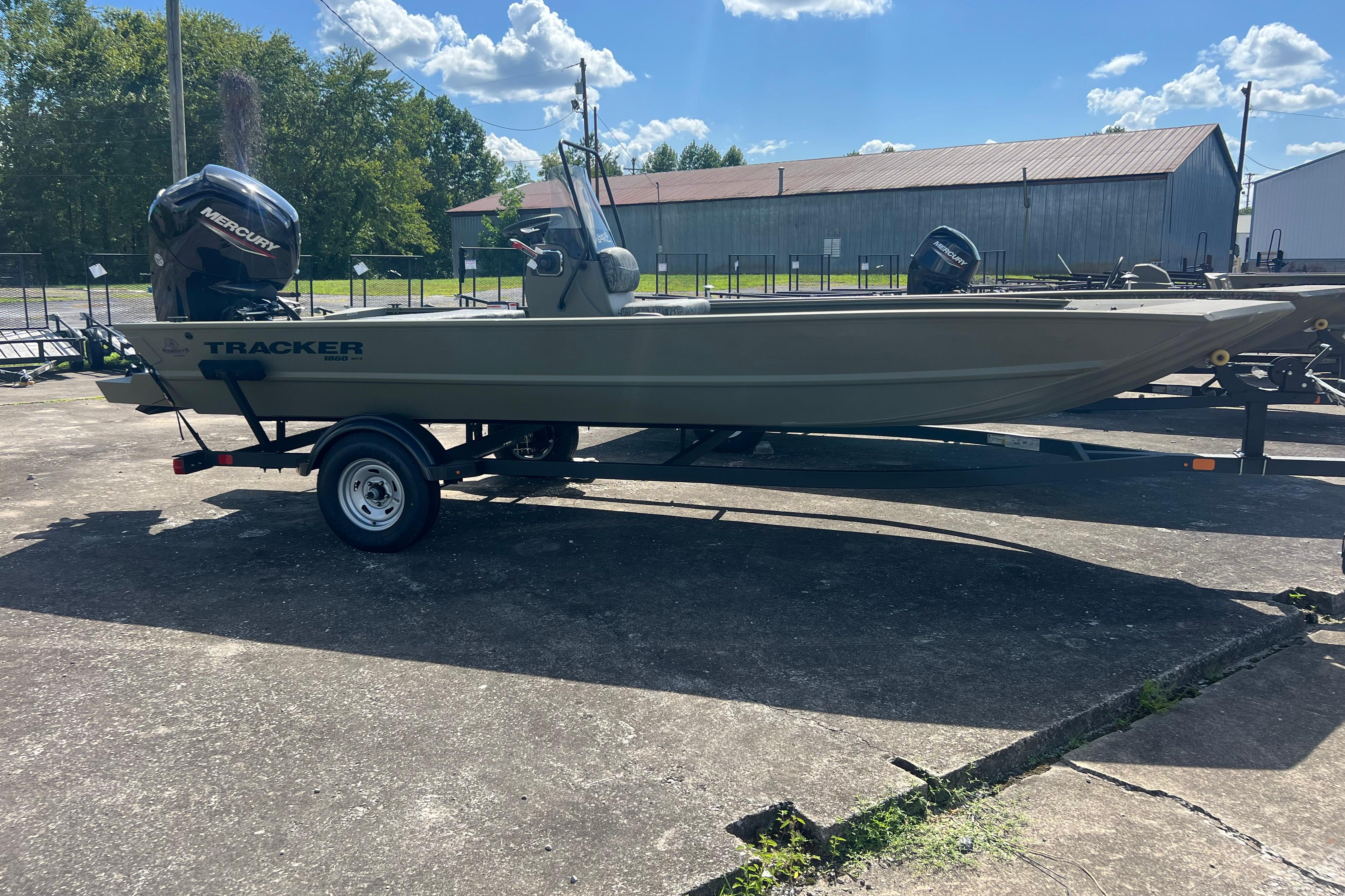 2026 Tracker Grizzly 1860 CC boat on trailer, outdoors under blue sky.