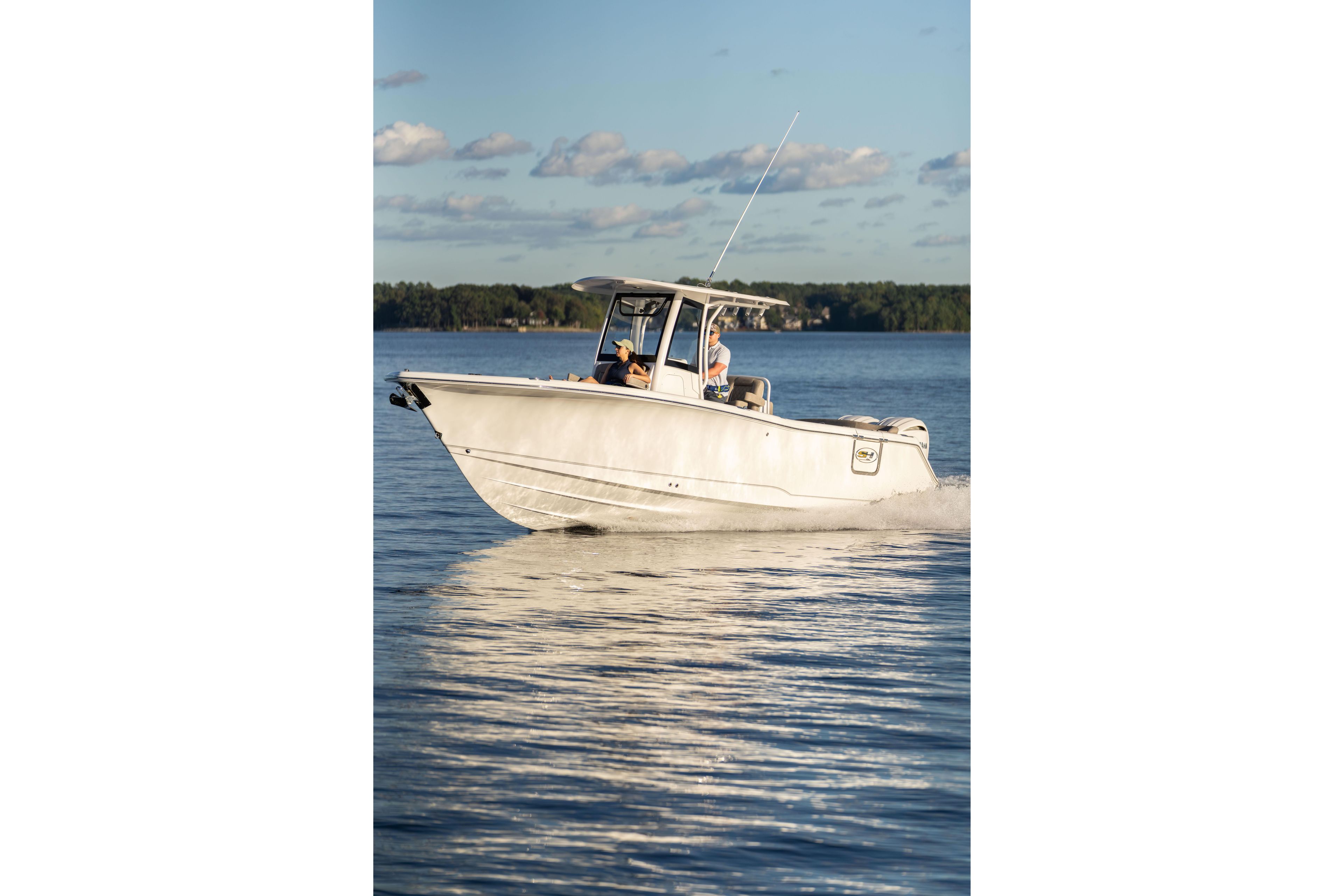2026 Sea Hunt Ultra 275 Coffin Box cruising on a serene lake under a clear sky.