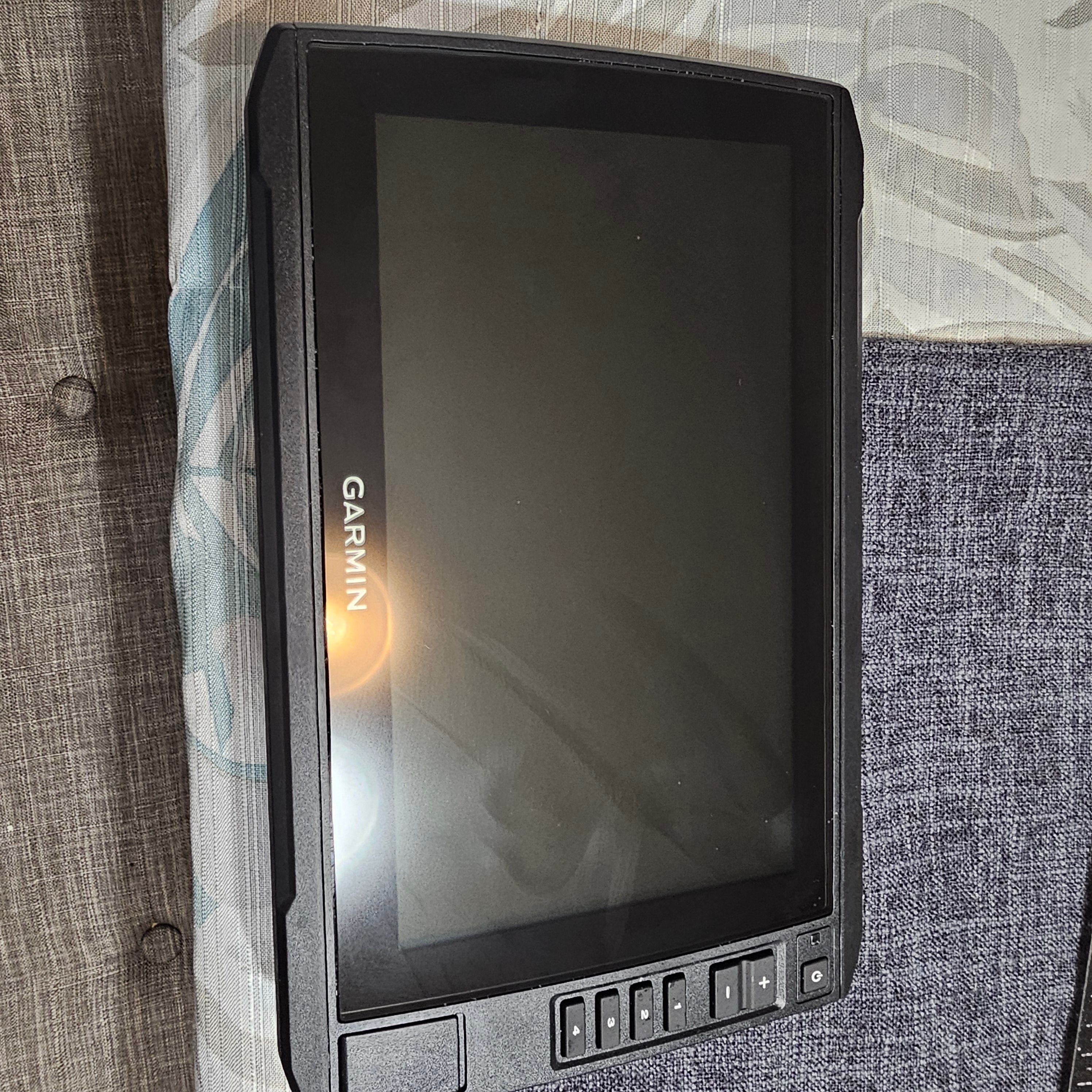 Garmin device on a fabric surface, featuring a sleek black design and control buttons.