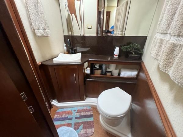 Compact bathroom in a 2009 Ovation 52 yacht with sink, toilet, and storage.