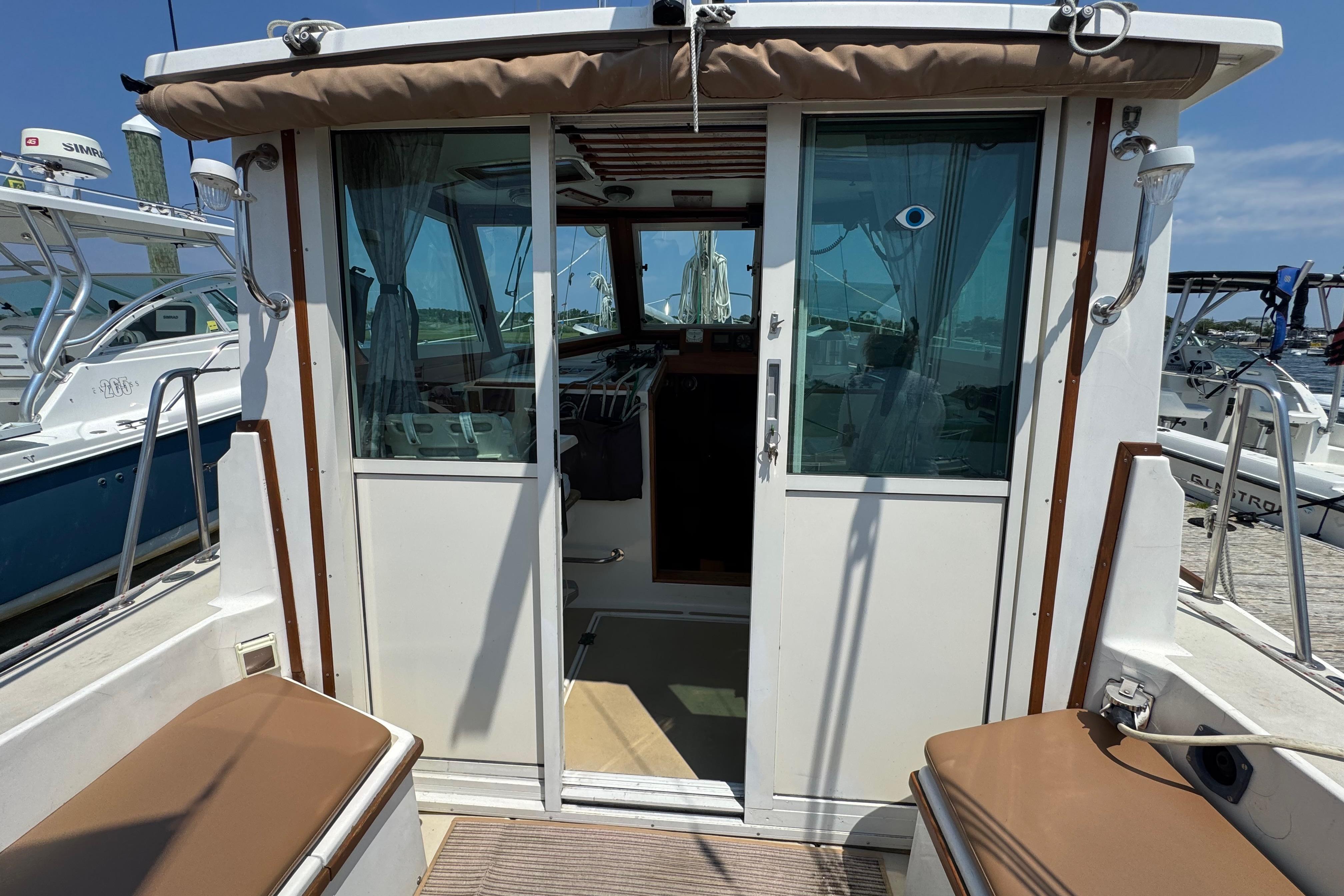 1989 Cape Dory 30 Motorsailer cockpit with sliding doors and seating, docked at marina.