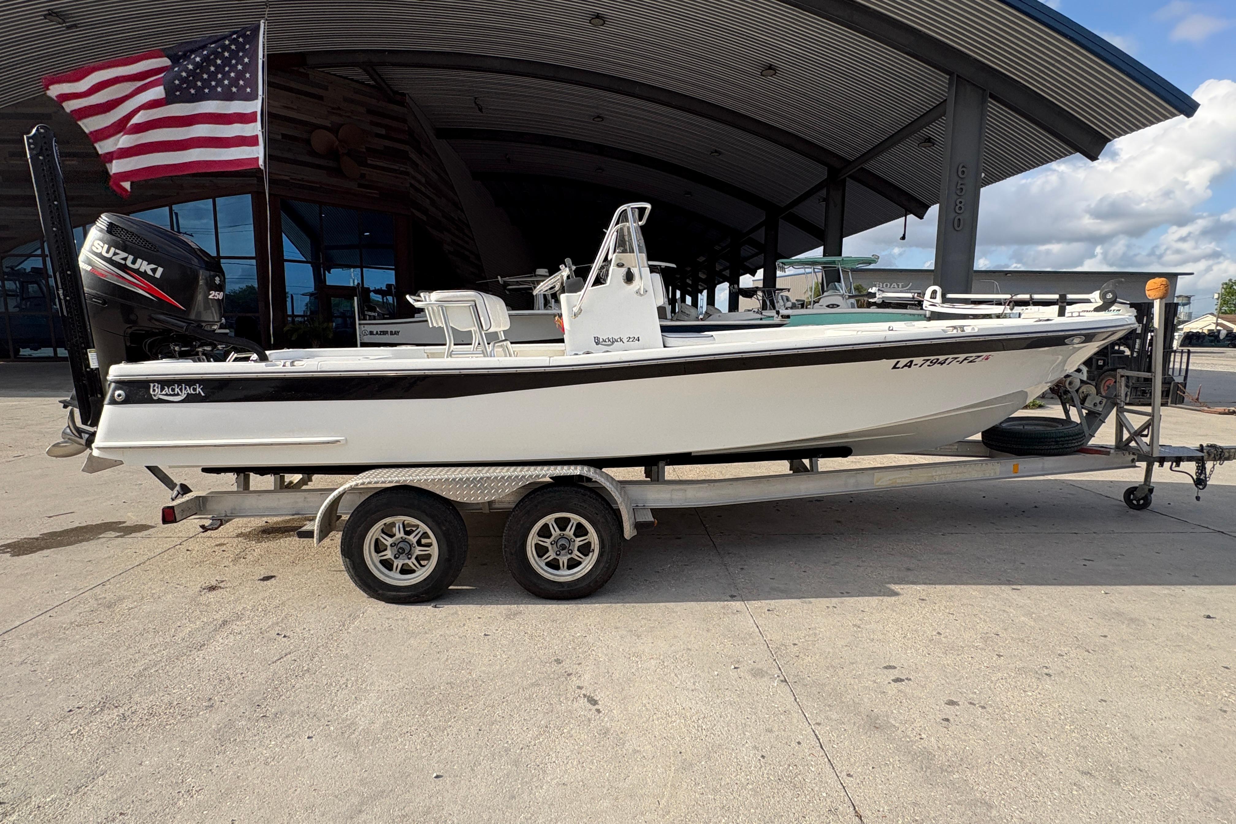 2012 BlackJack 224 boat on trailer with Suzuki engine, parked under a metal canopy.