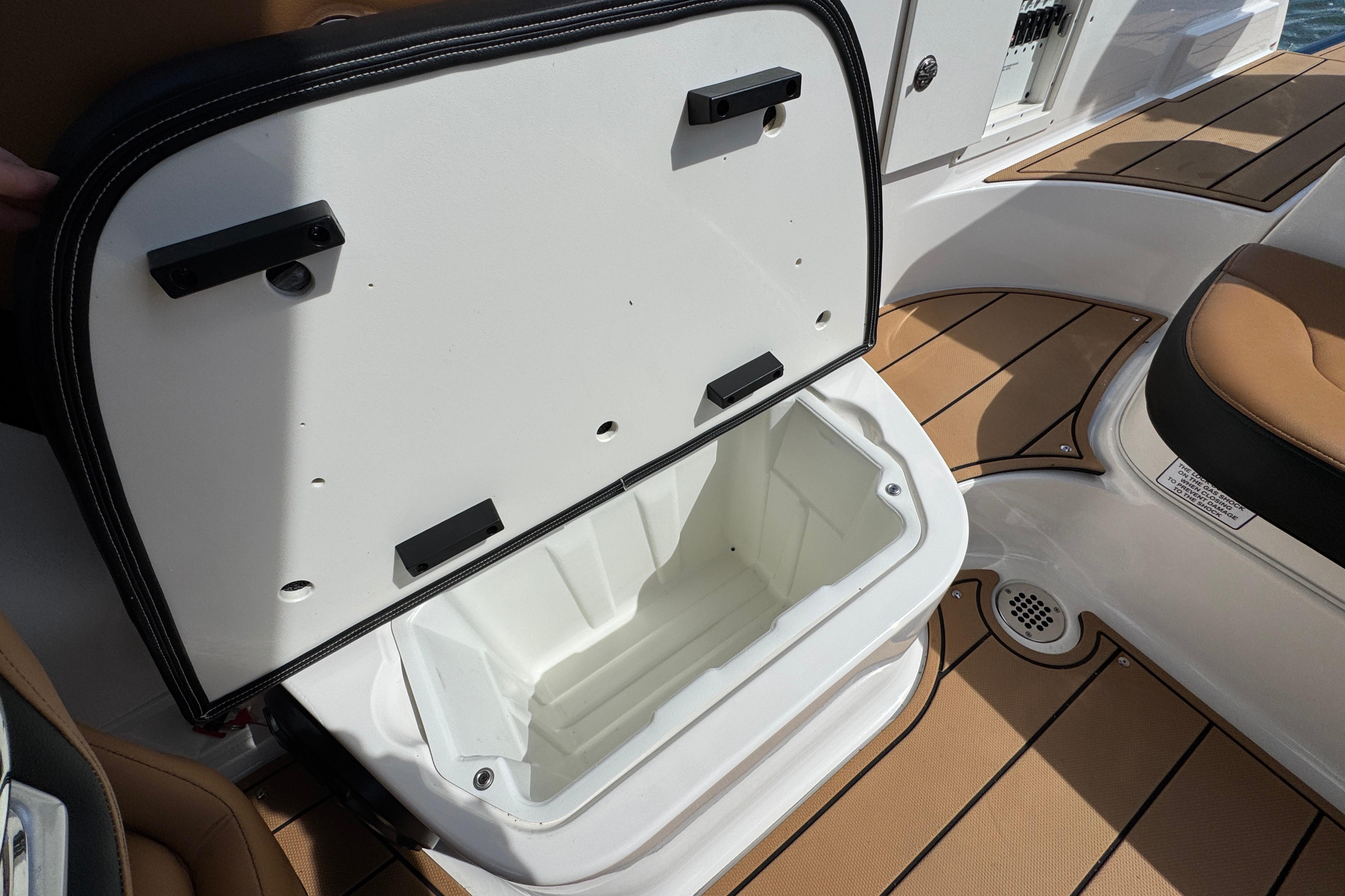 2023 Chaparral 26 Surf boat interior with open storage compartment and teak flooring.