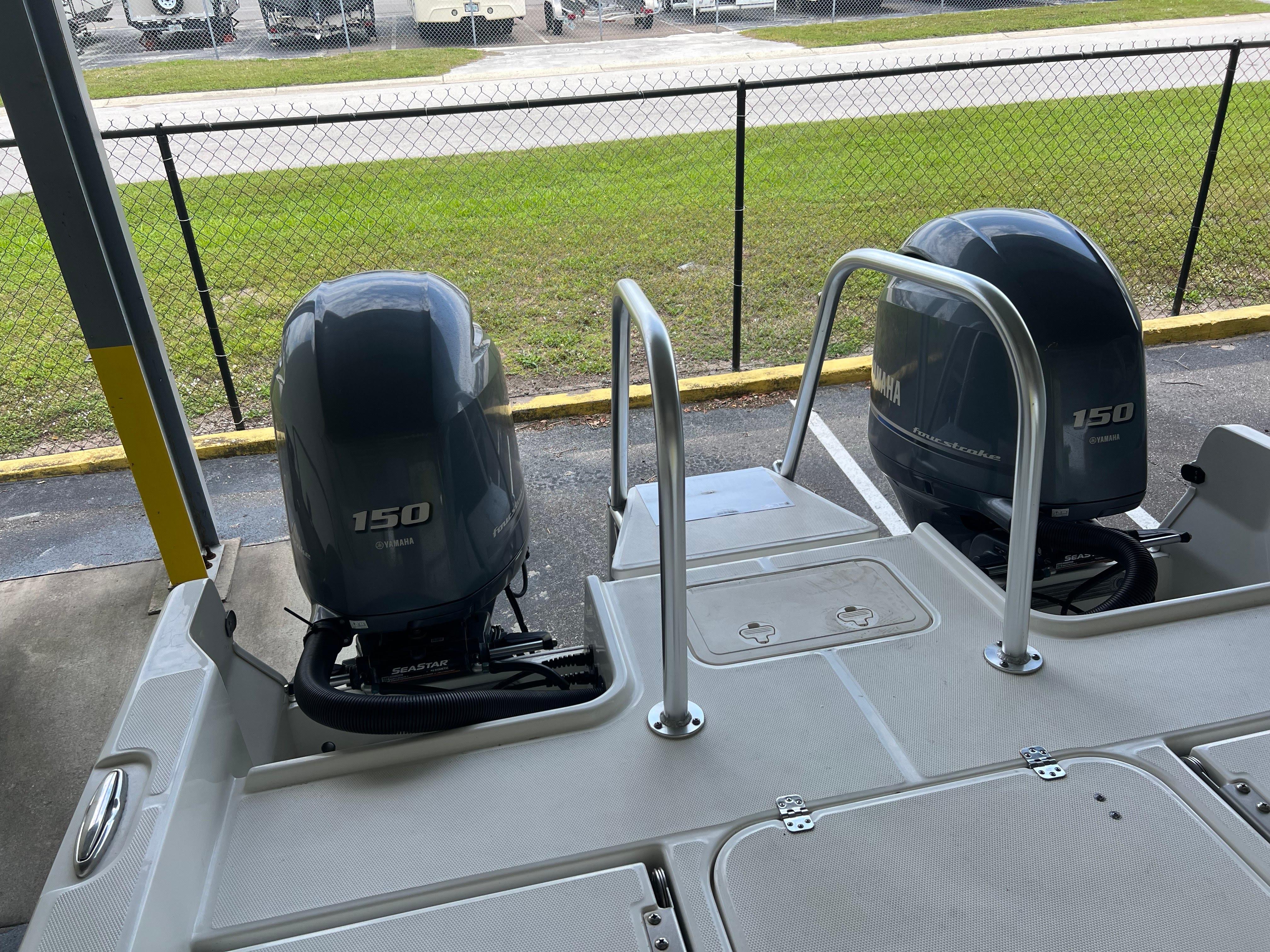 2022 World Cat 235 CC boat with dual 150 horsepower engines, docked near a fence.