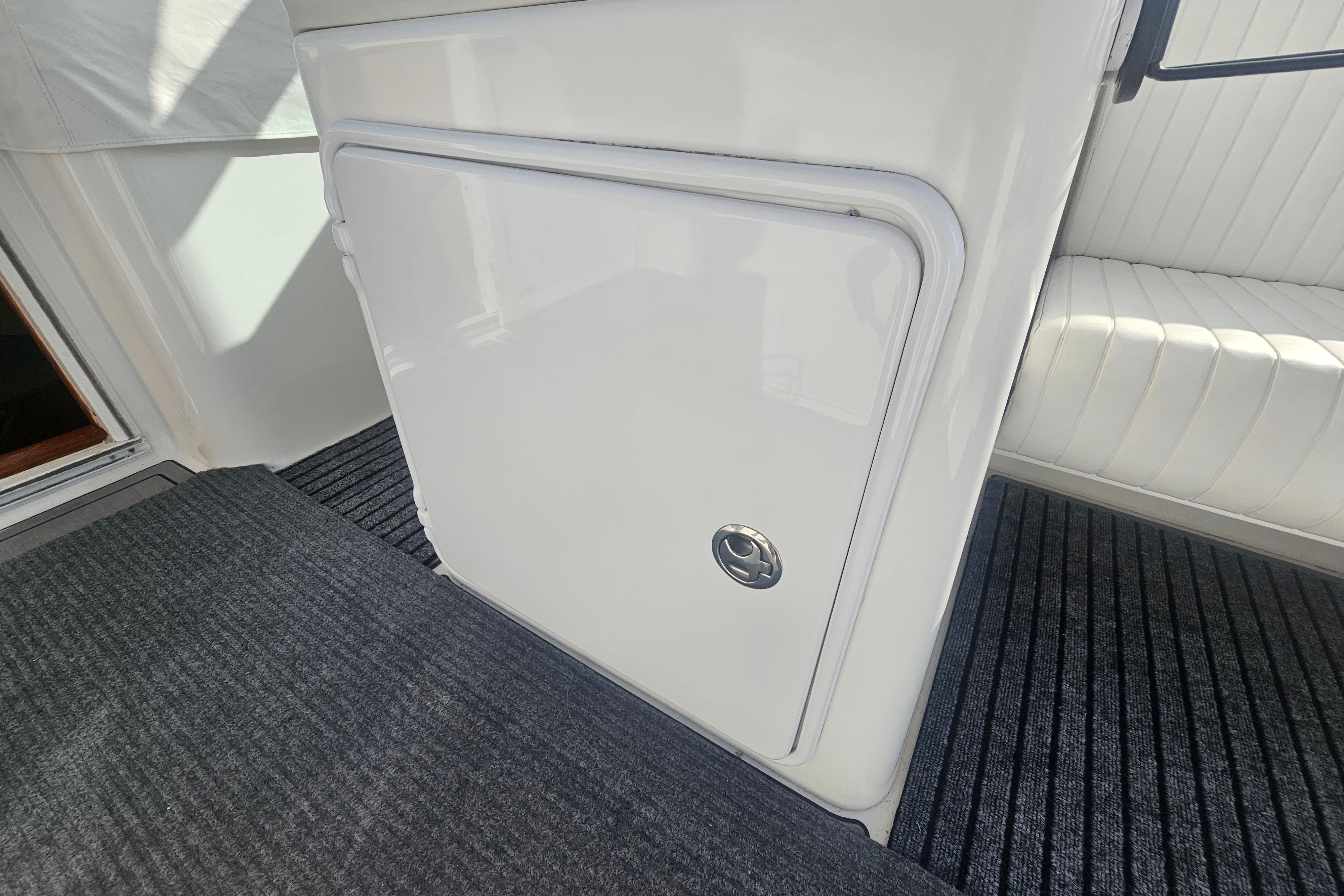 2003 Topaz 32 Express boat interior with white storage compartment and striped flooring.