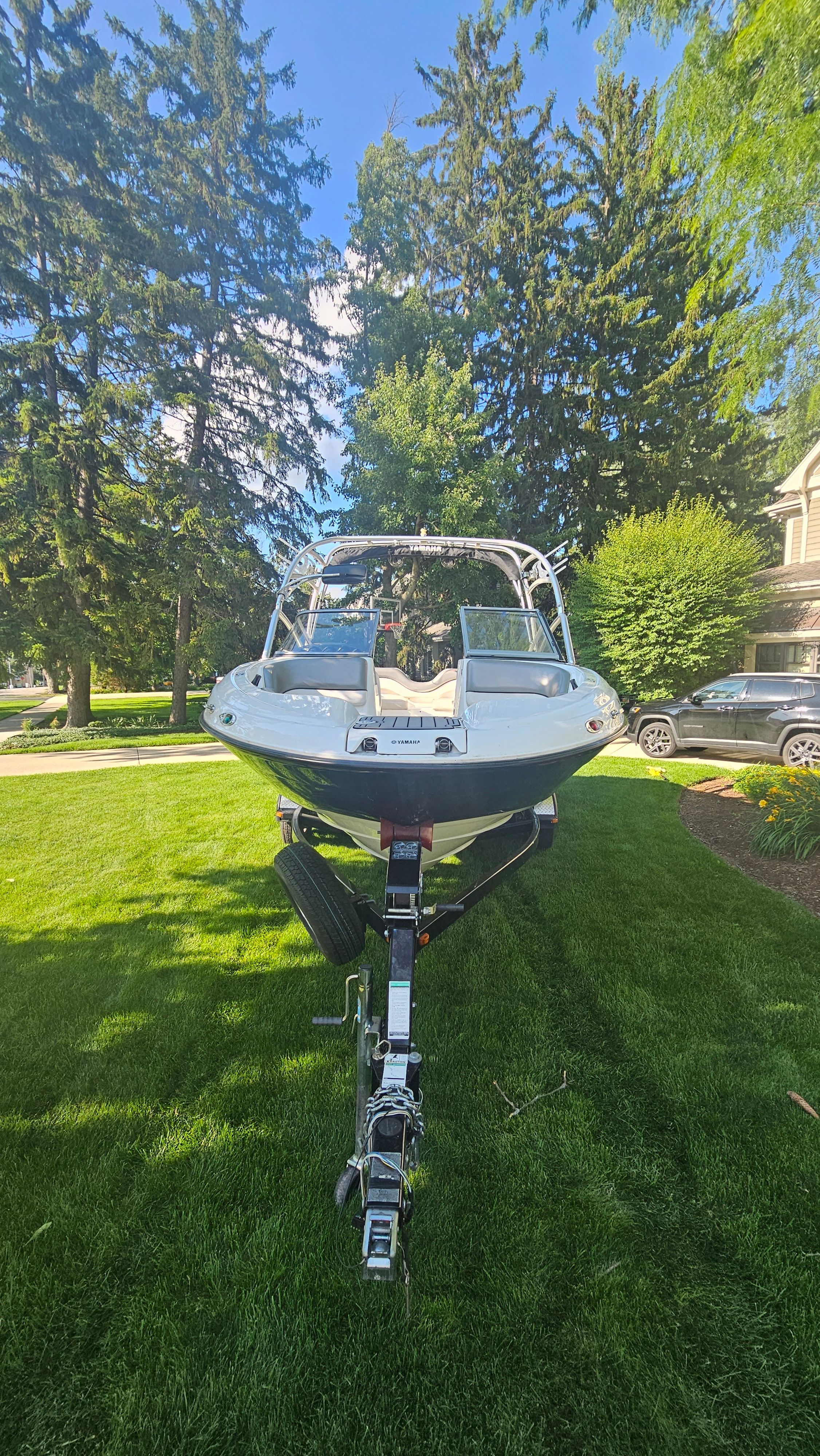 A 2010 Yamaha AR210 boat on a trailer, parked on a green lawn.
