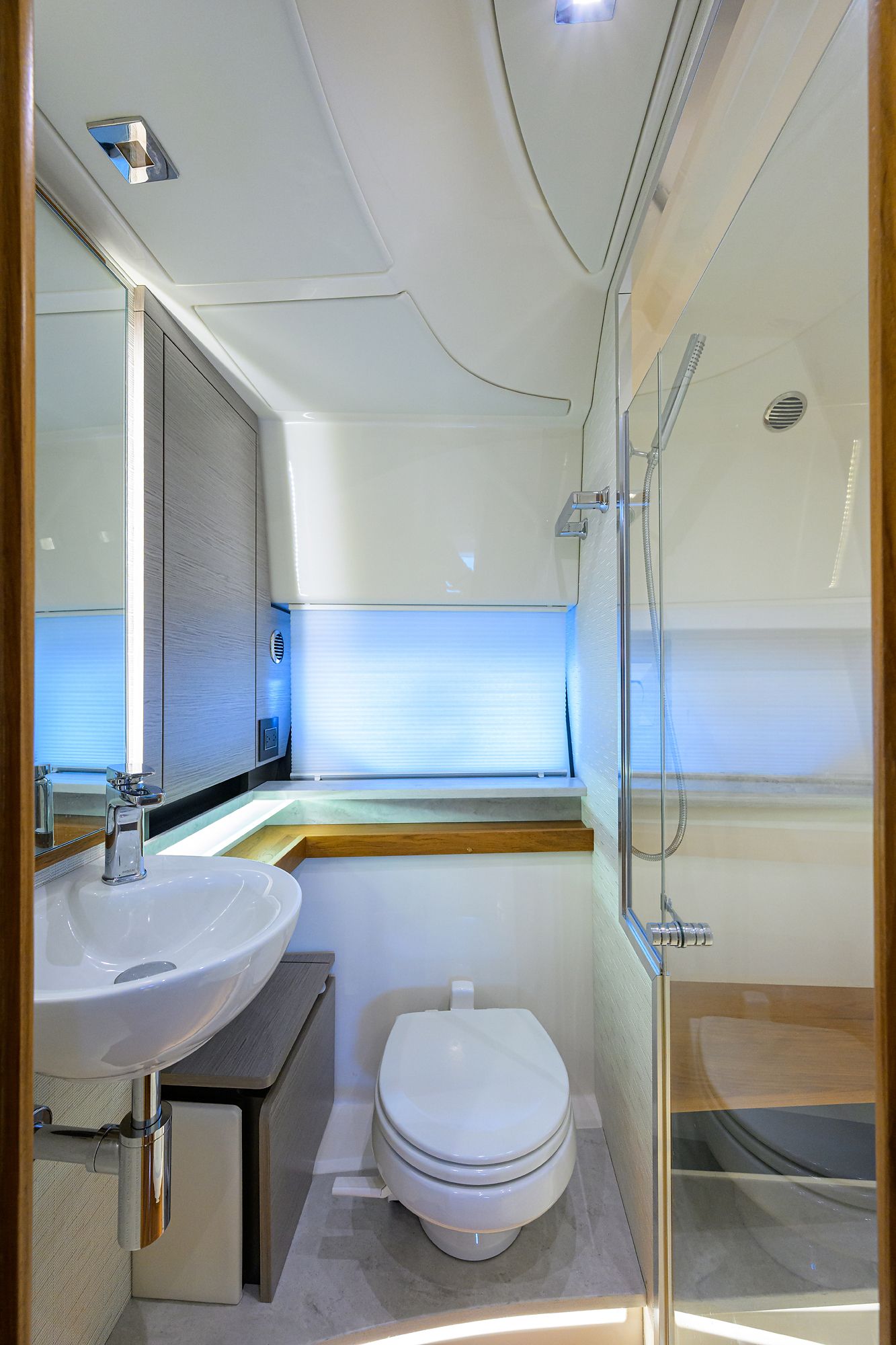 Modern yacht bathroom with sink, toilet, and shower.