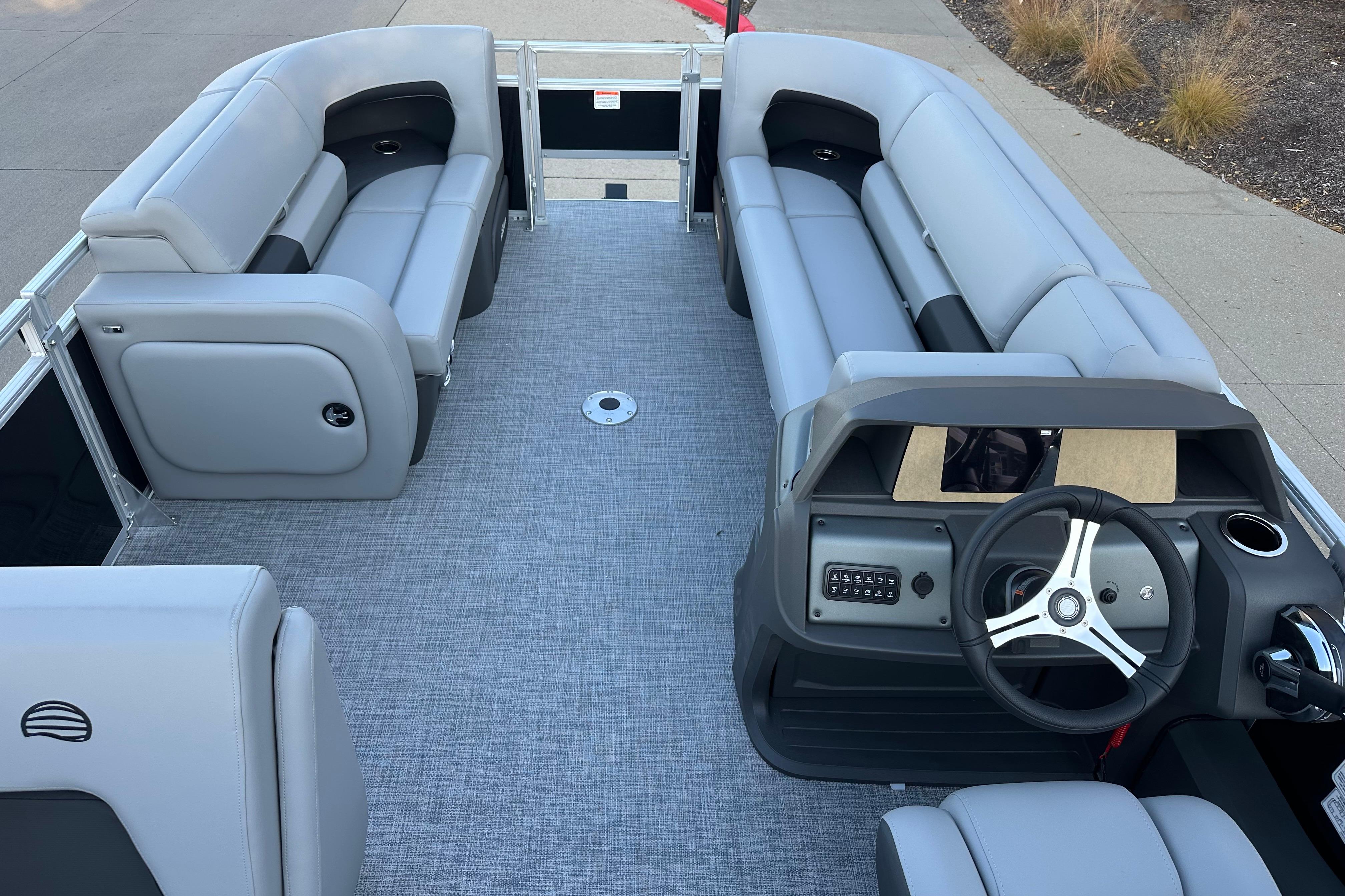 2026 Sun Tracker SportFish 22 DLX pontoon boat interior with gray seating and steering console.