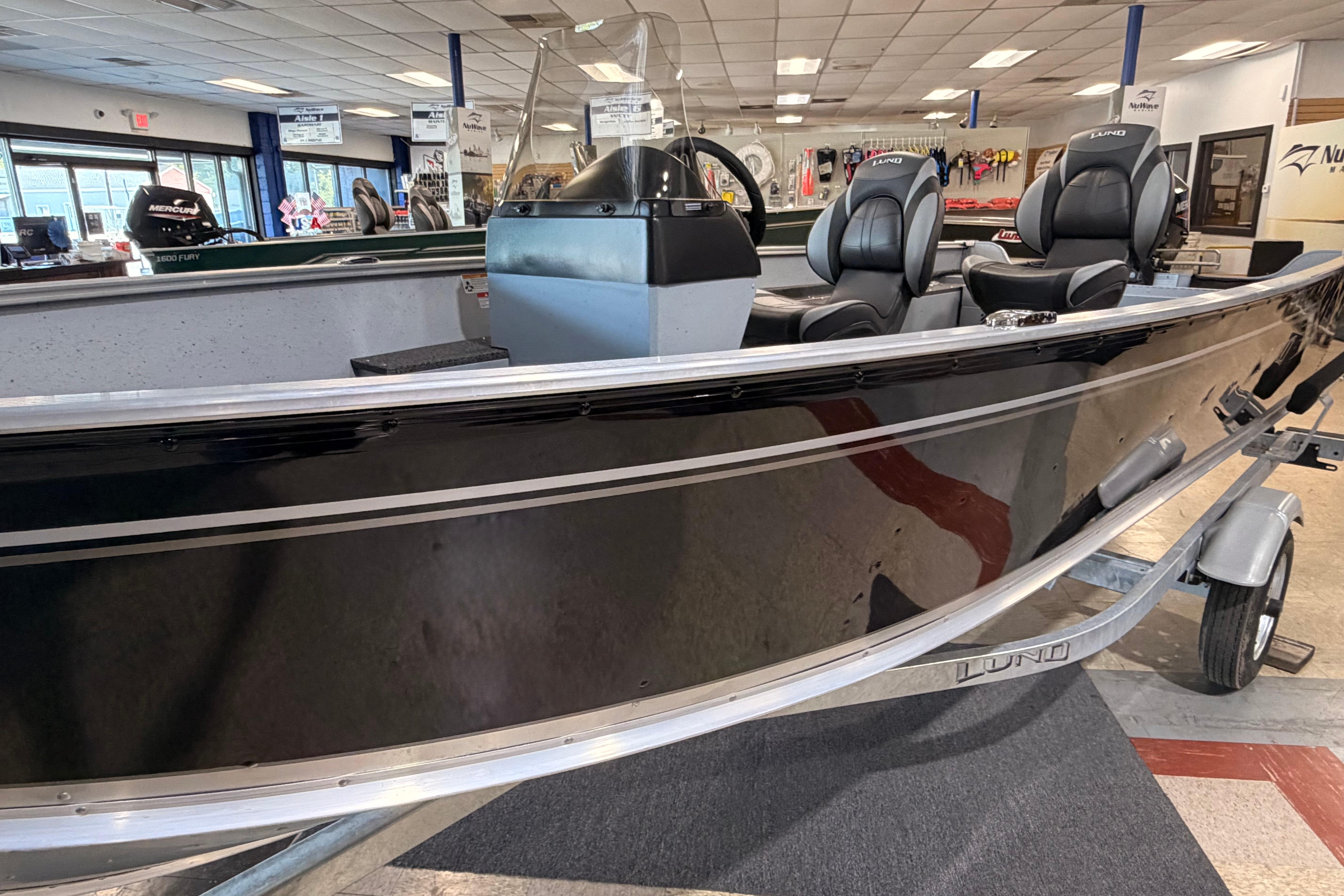 2027 Lund 1600 Fury SS boat in showroom, featuring sleek black design and comfortable seating.