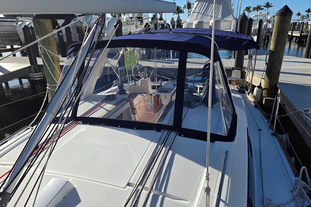 2023 Beneteau Oceanis 38.1 sailboat docked at marina, featuring blue canopy and sleek design.