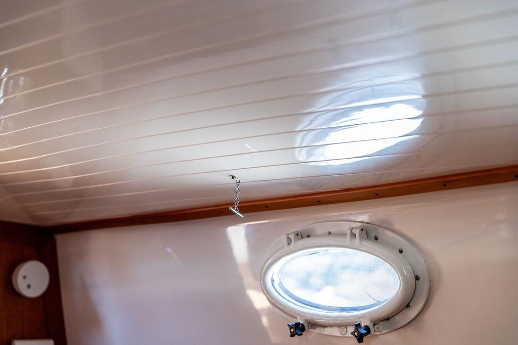 Interior view of 2000 Hinckley Picnic Boat 36 Classic with porthole and wooden trim.
