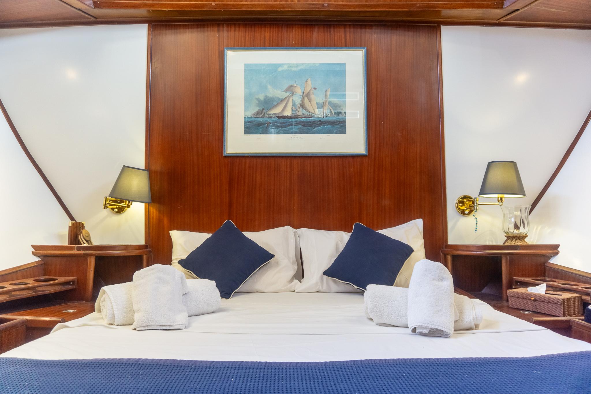 Luxurious cabin interior on a 1969 Psarros Shipyard yacht, featuring elegant bedding and nautical decor.