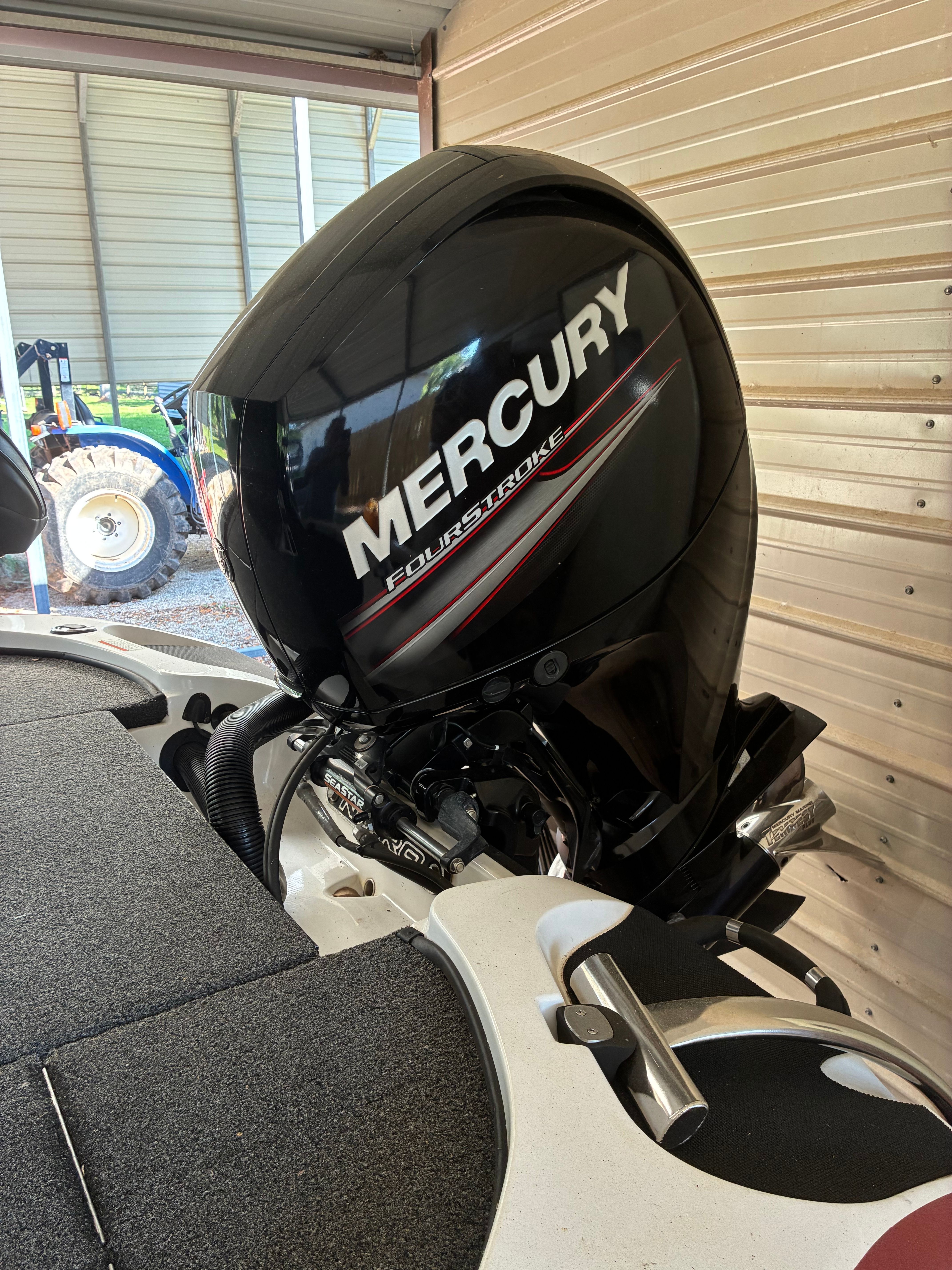 A Mercury four-stroke engine is attached to a boat in a covered area.