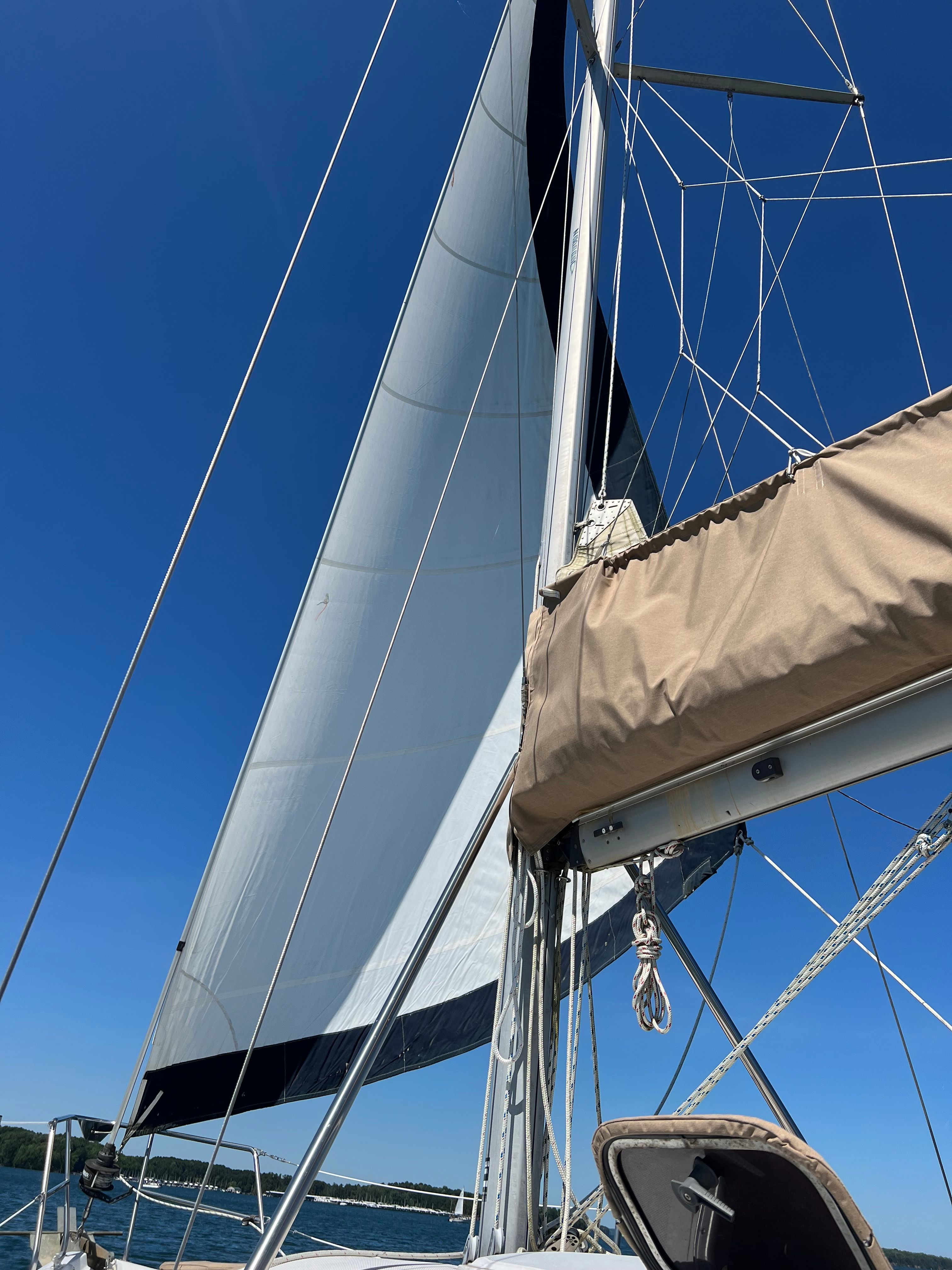 Sailboat with white sails under a blue sky.