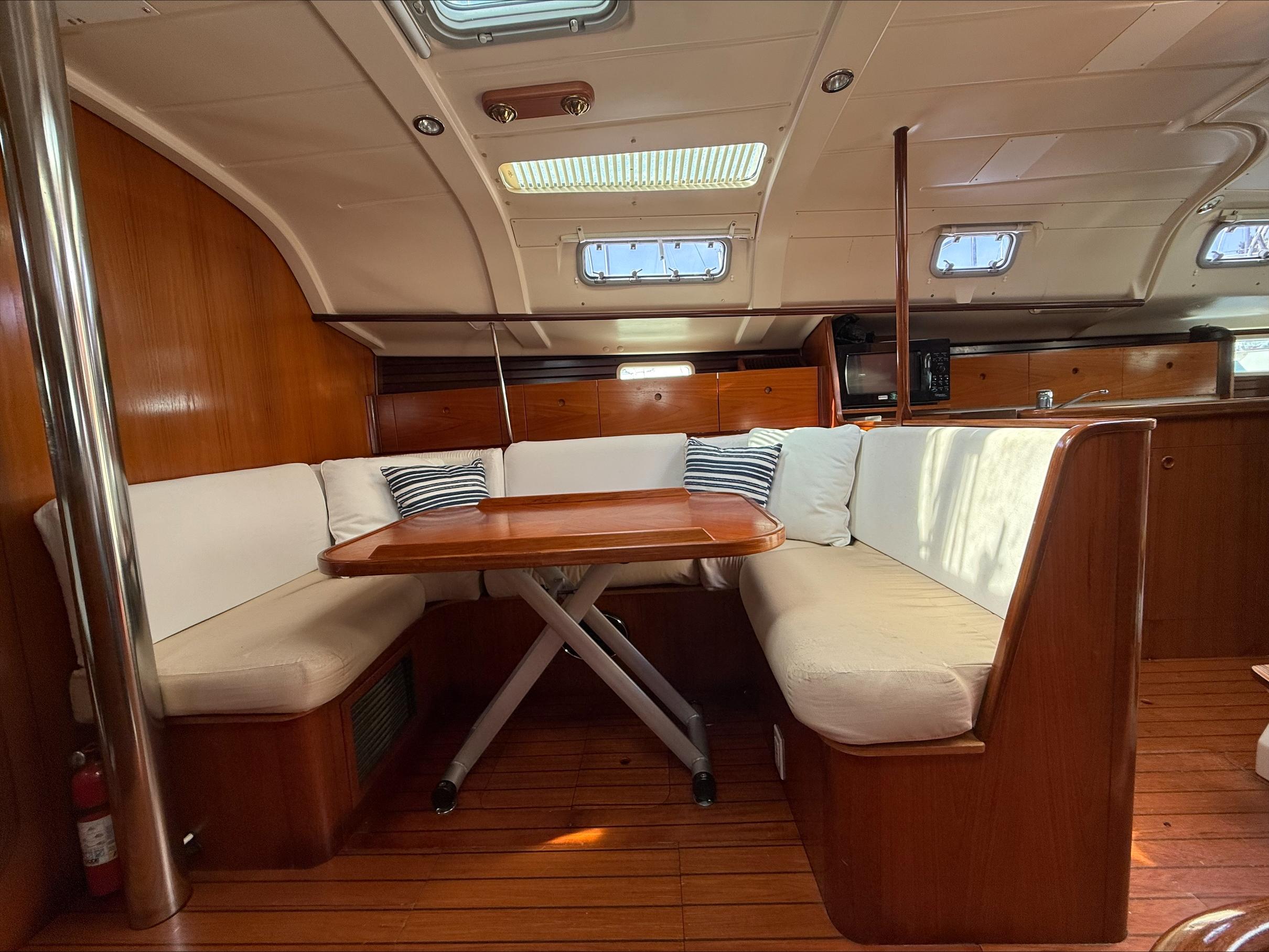 Interior of 1993 Beneteau Oceanis 400 sailboat with wooden dining area and cushioned seating.