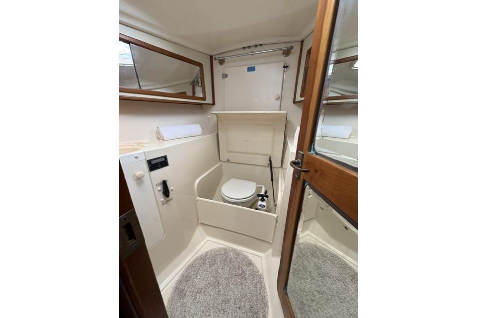 Compact bathroom in 2002 Saga 43 yacht with toilet, mirror, and wooden door.