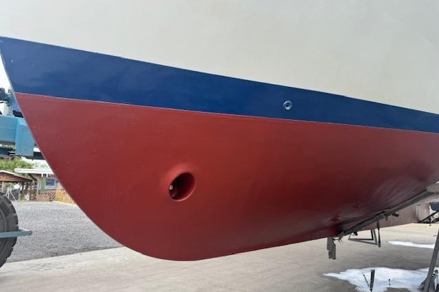 1986 Krogen 42 Classic boat hull with red and blue paint, docked on land.
