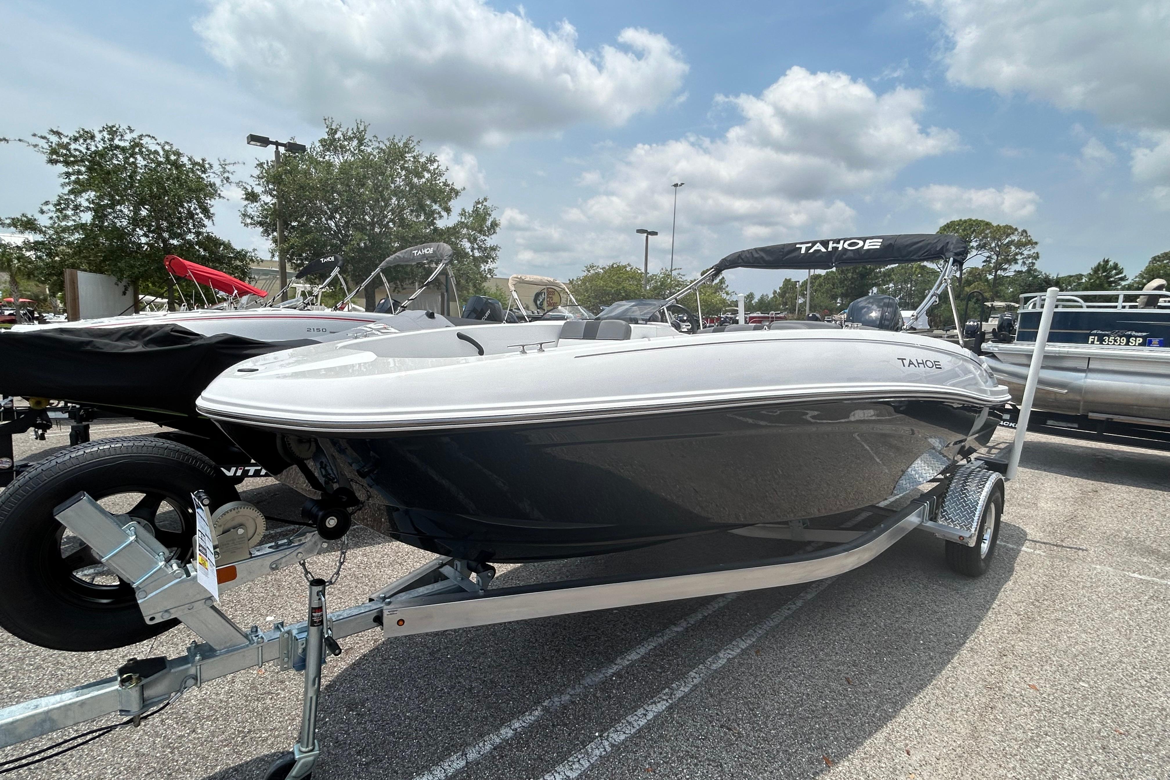 2026 Tahoe T18 boat on trailer in outdoor showroom under cloudy sky.