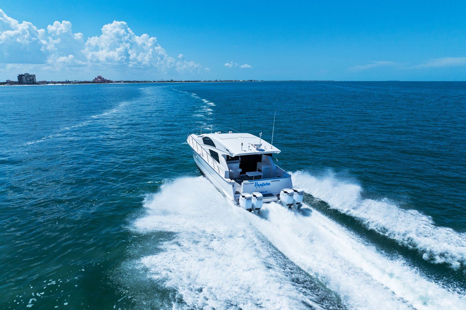 Catamaran on the sea with four outboard engines, leaving a white wake on blue water.