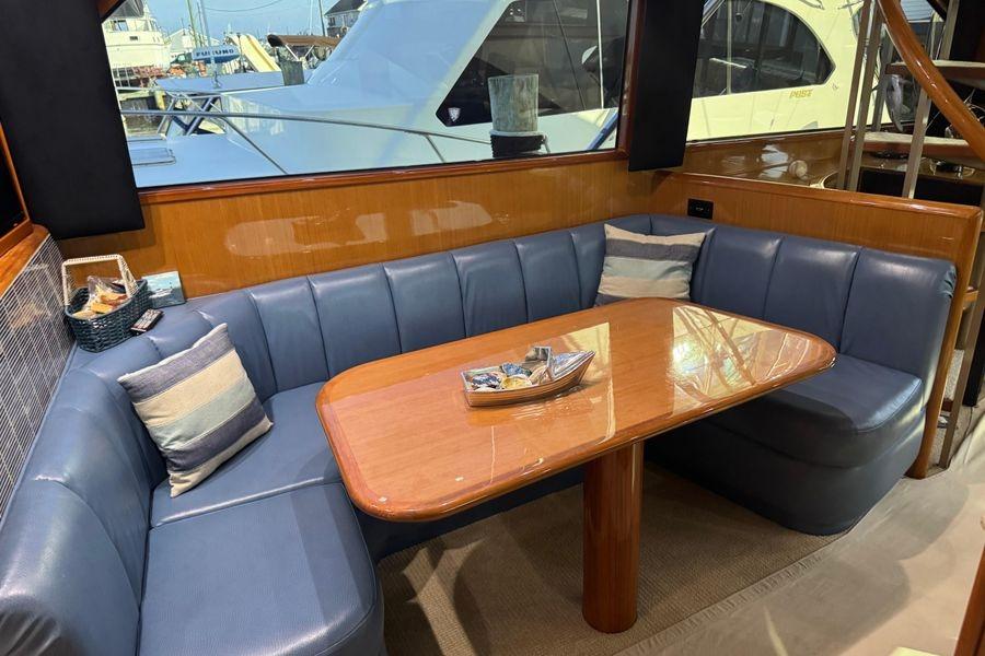 Luxurious interior of 2002 Viking 61 Enclosed Bridge yacht with blue seating and wooden table.