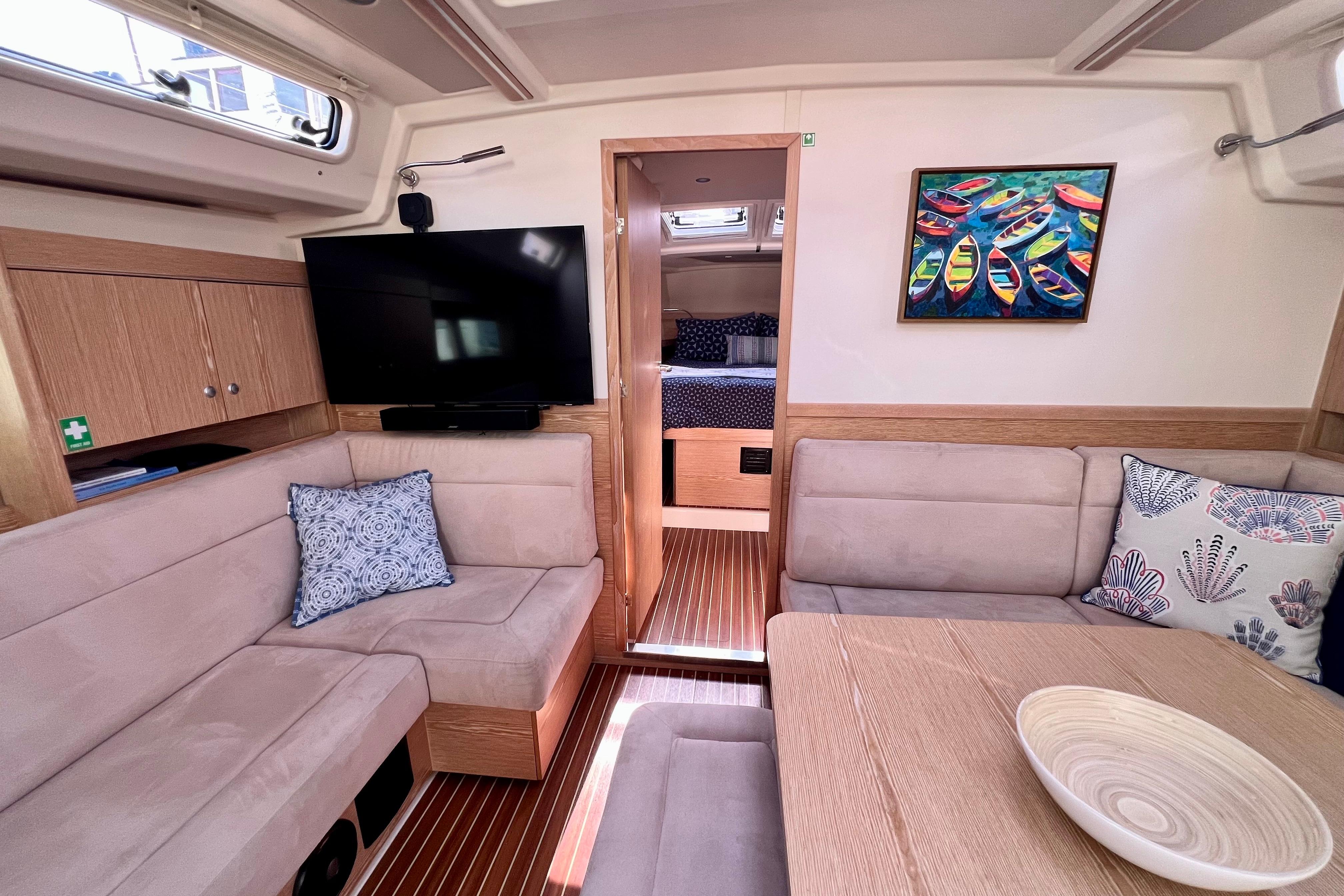 Interior of 2016 Hanse 455 yacht with cozy seating, TV, and colorful artwork.