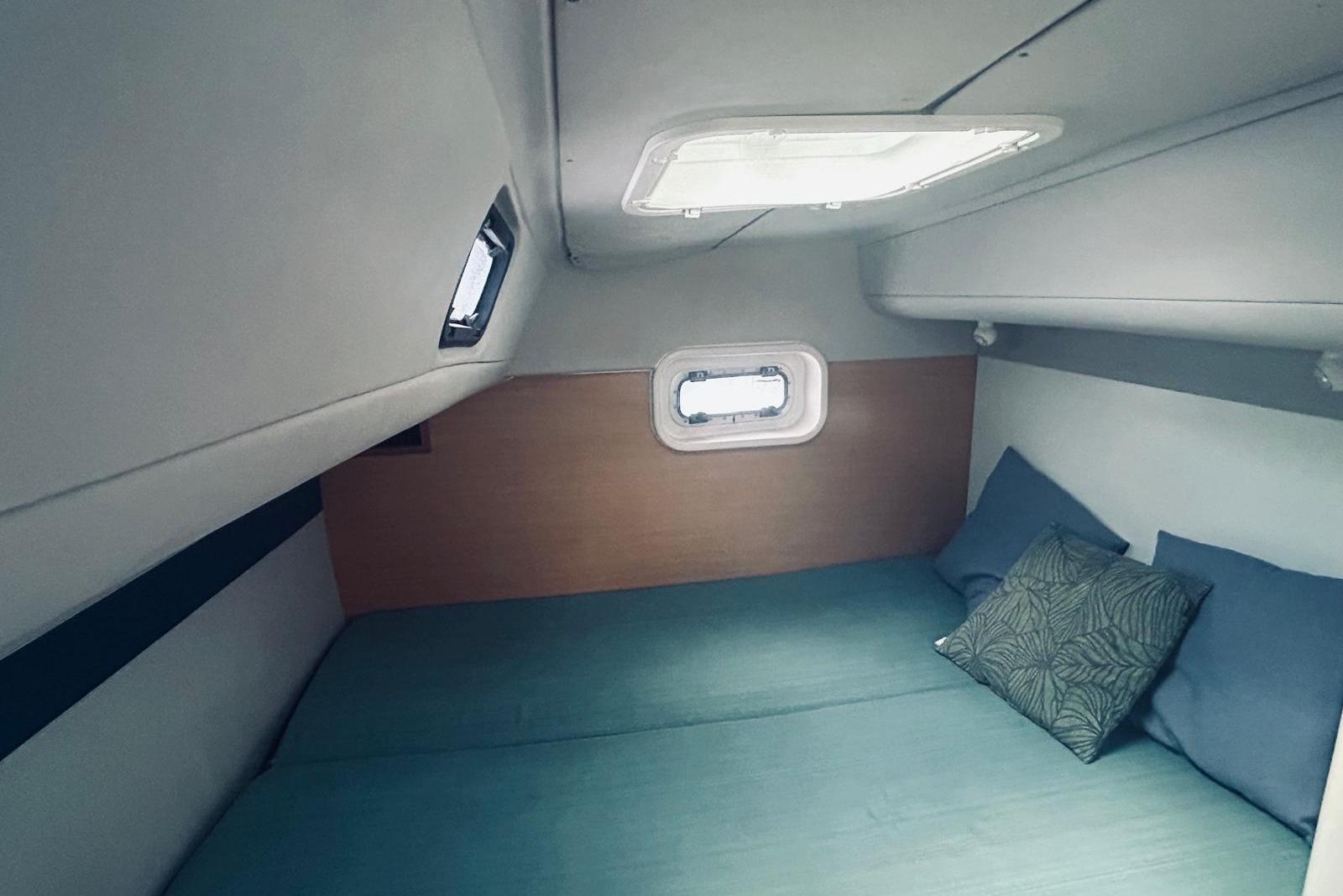 Cozy cabin interior of 2001 Robertson & Caine Leopard yacht with teal bedding and pillows.