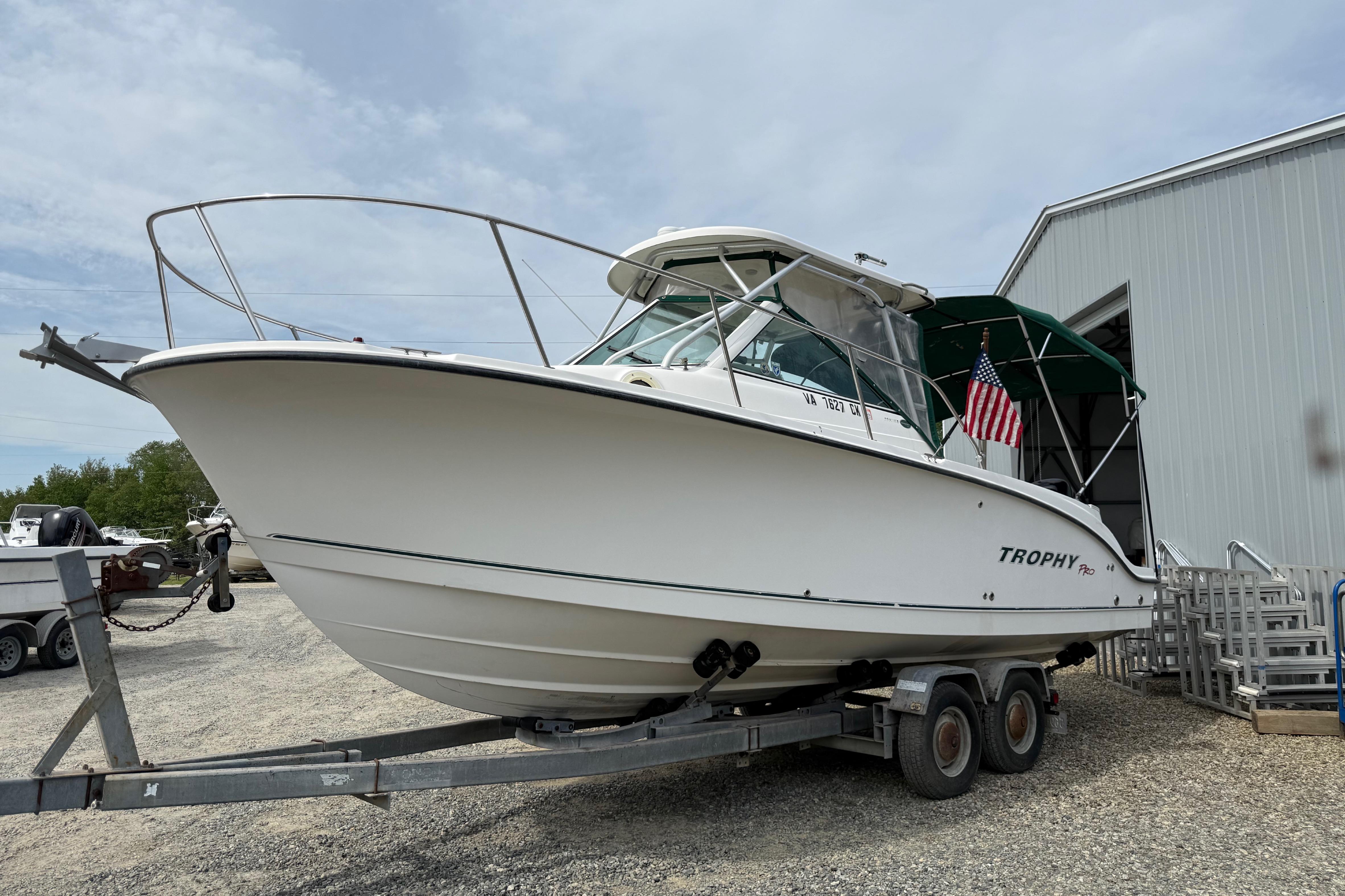 2006 Trophy 2502 Walkaround boat on trailer near a metal building.