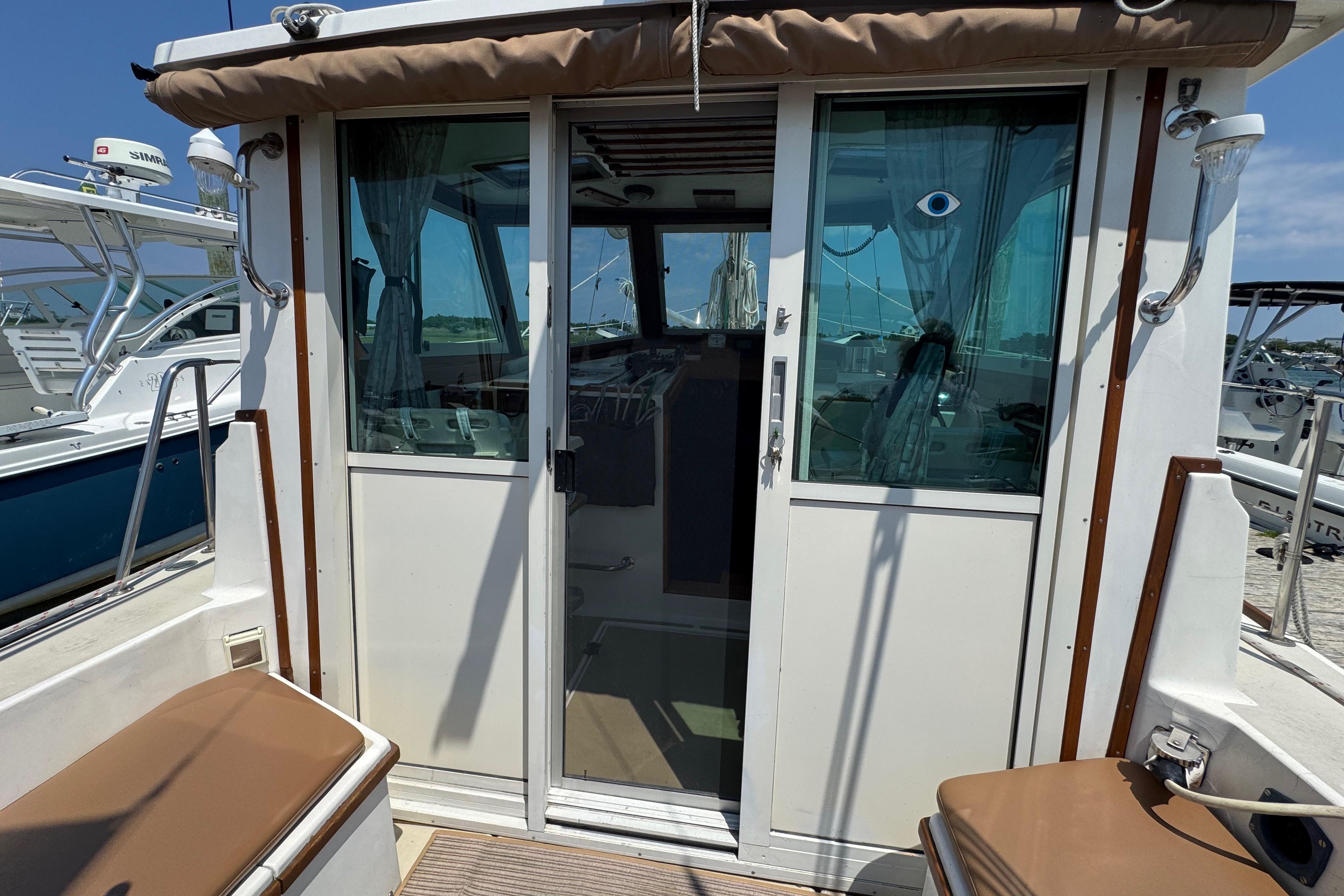 1989 Cape Dory 30 Motorsailer with sliding glass doors and cushioned seating on deck.