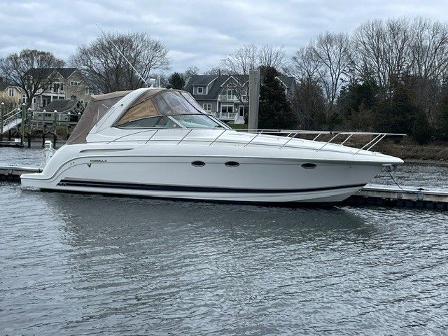 A white motor yacht is docked in calm waters, with houses visible in the background.