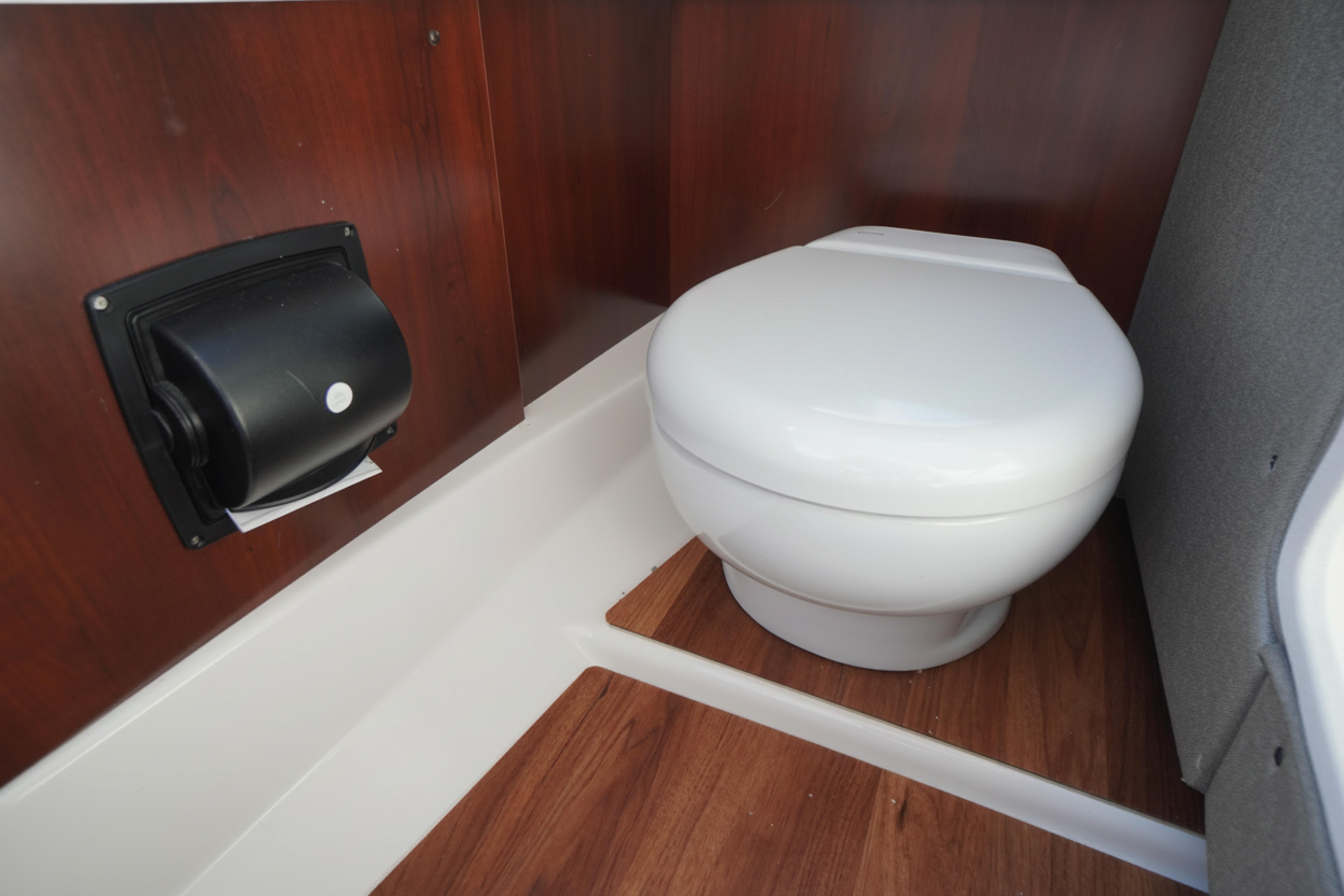 2026 Chaparral 270 OSX boat interior with modern toilet and wood paneling.