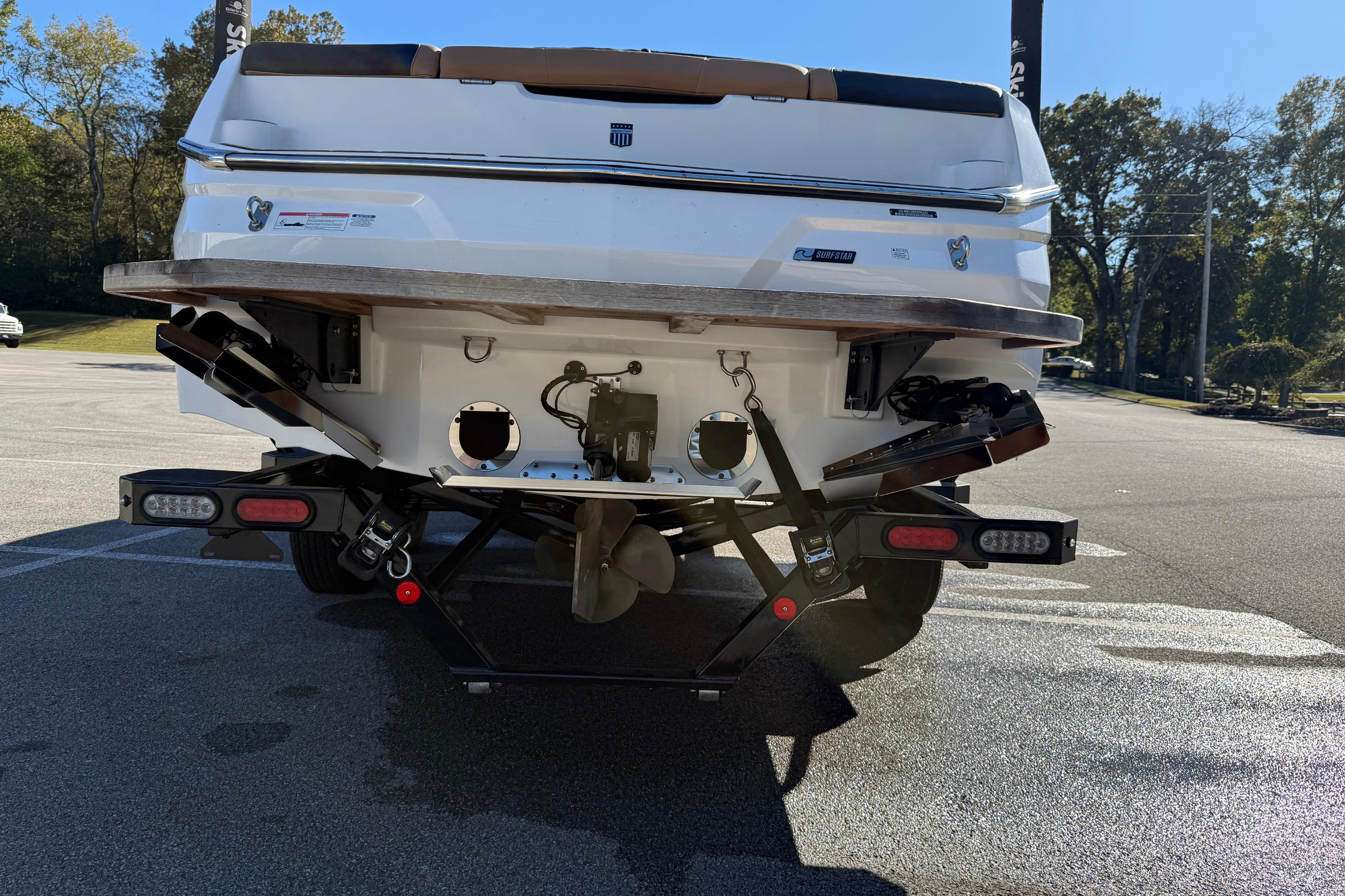 Rear view of 2022 MasterCraft NXT24 boat on trailer in sunny parking lot.