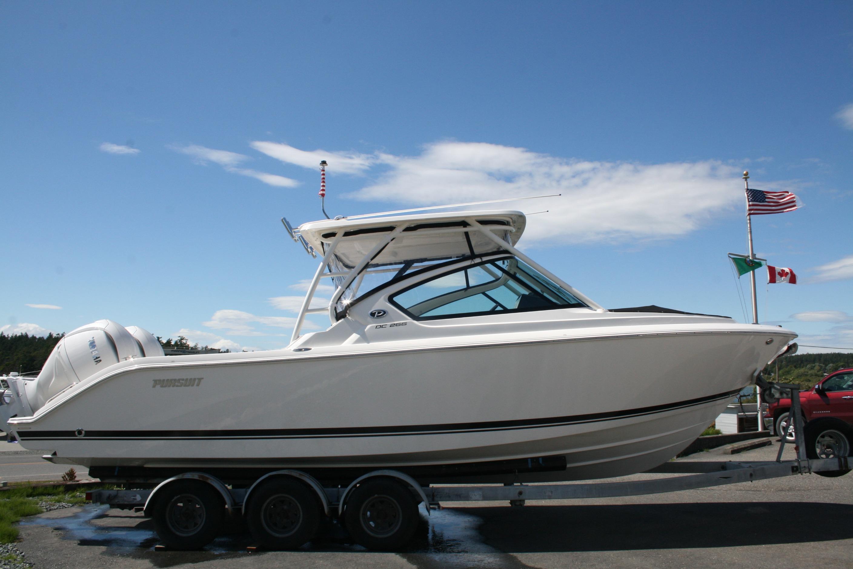 2026 Pursuit DC 266 Dual Console boat on trailer, flags in background, clear sky.