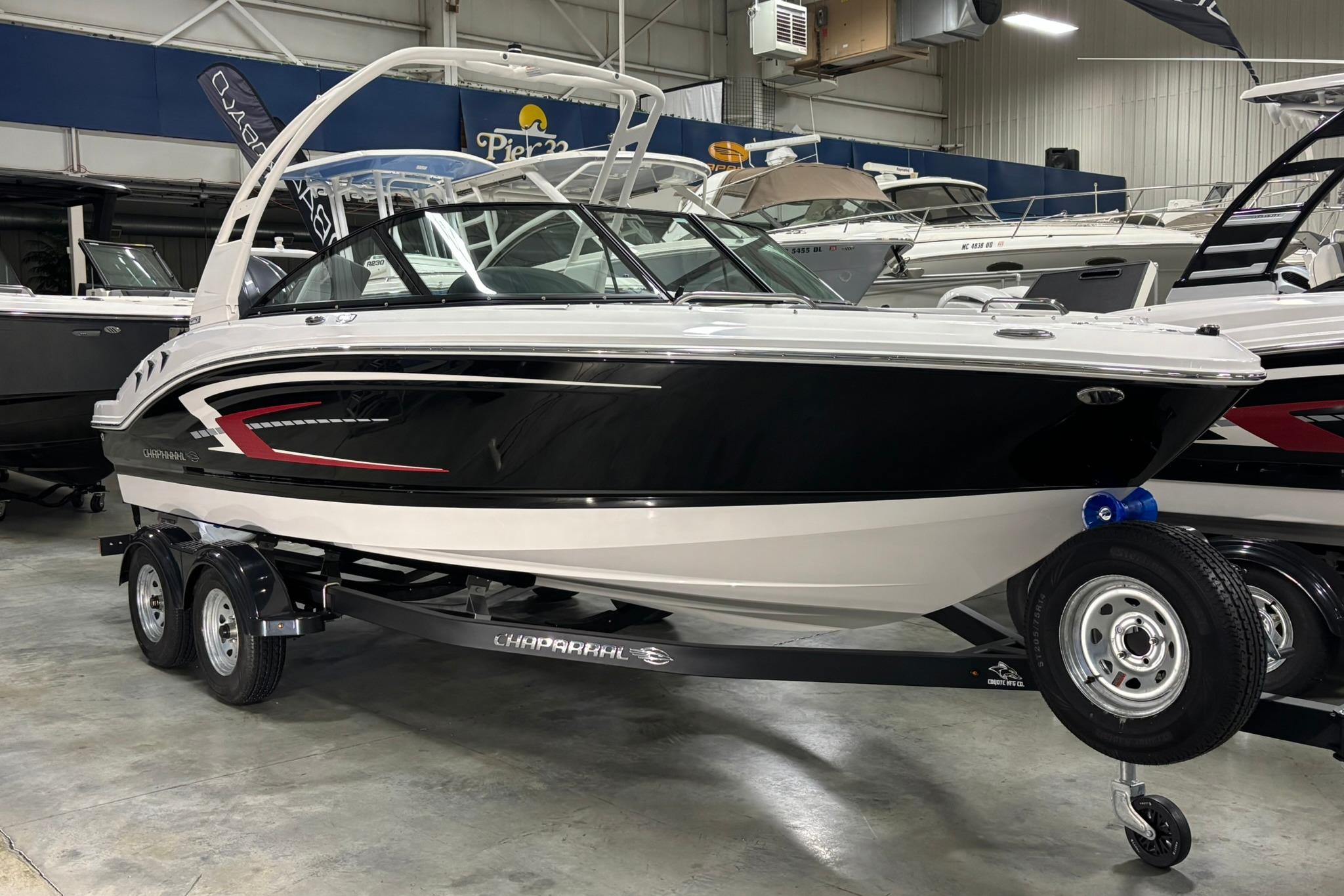 2026 Chaparral 21 SSi OB boat on trailer in showroom, sleek black and white design.