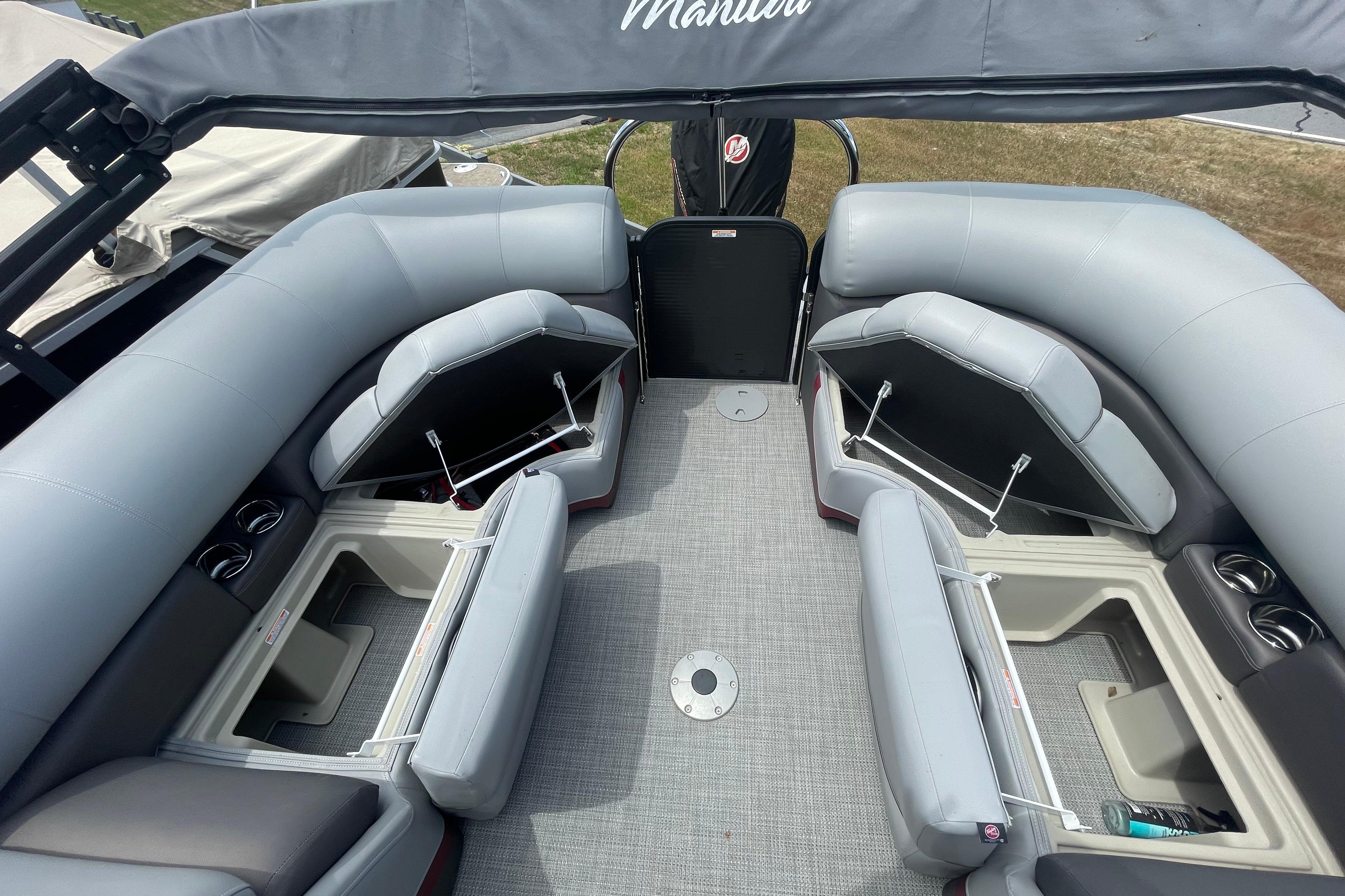 2022 Manitou 23 Oasis pontoon boat interior with gray seating and storage compartments.