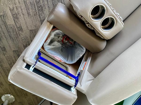 A seat with built-in trash bin and cup holders on a boat.