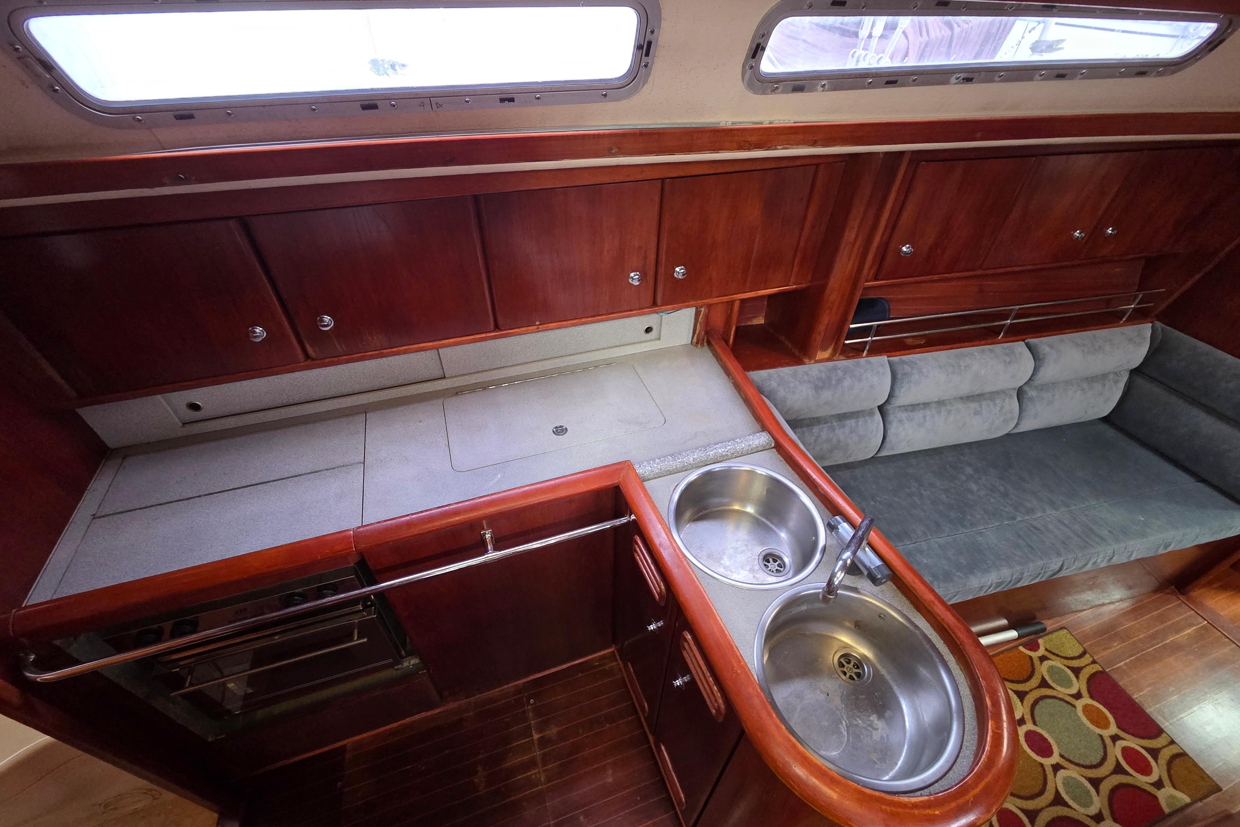 Interior of 1995 Moody 38 yacht with wooden cabinets, dual sink, and cushioned seating.
