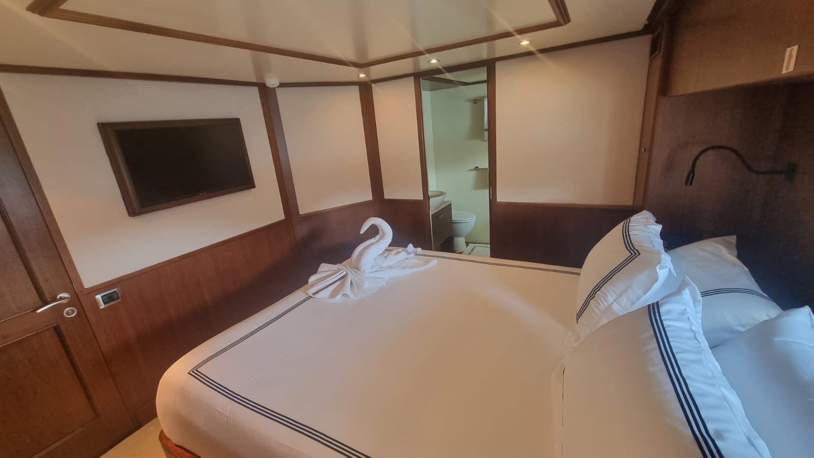 Luxurious bedroom in 2000 Benetti Classic 115 yacht with elegant decor and swan towel.