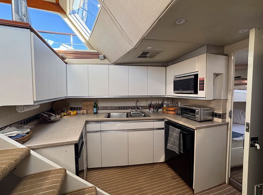 The kitchen of a yacht with white cabinets and modern appliances.