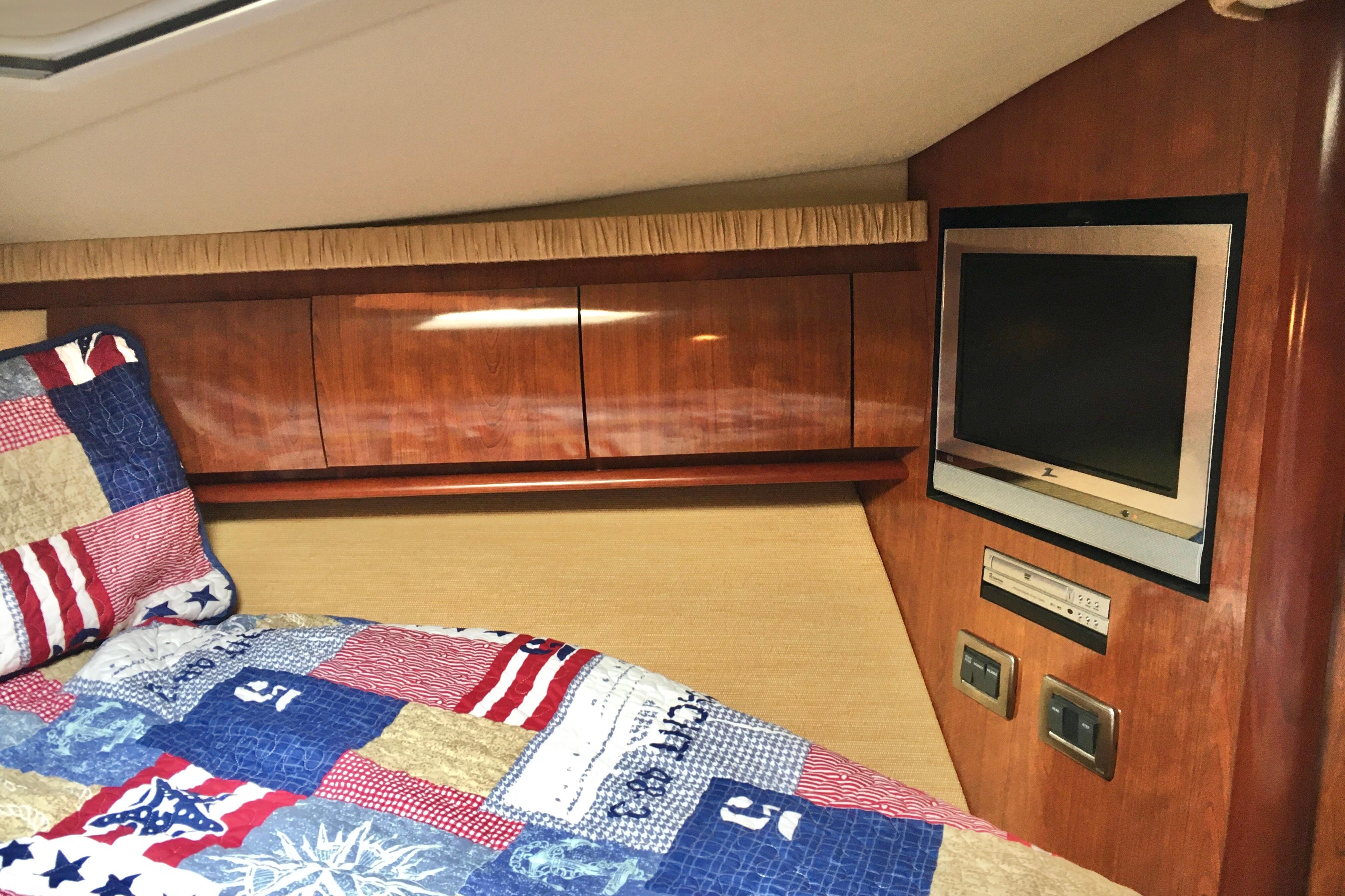 Cozy cabin interior of 2005 Sea Ray 420 Sundancer with TV and colorful bedding.