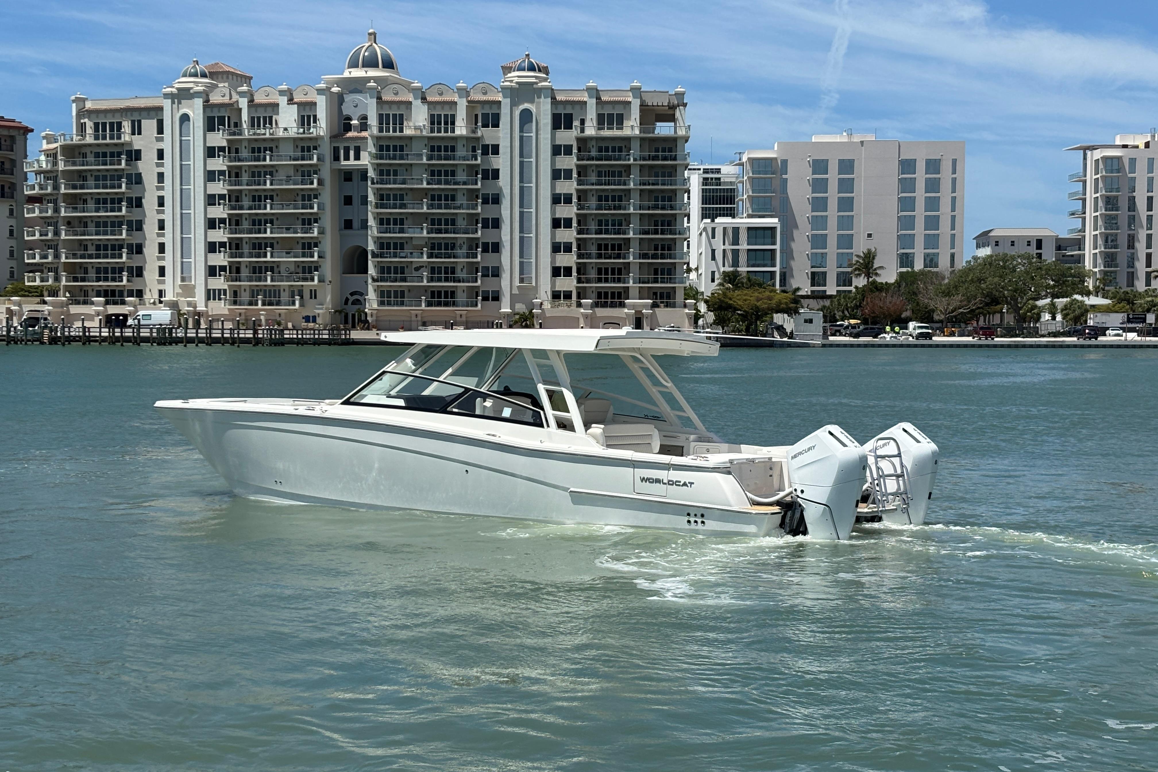2026 World Cat 400 DC-X Island boat cruising near waterfront buildings.
