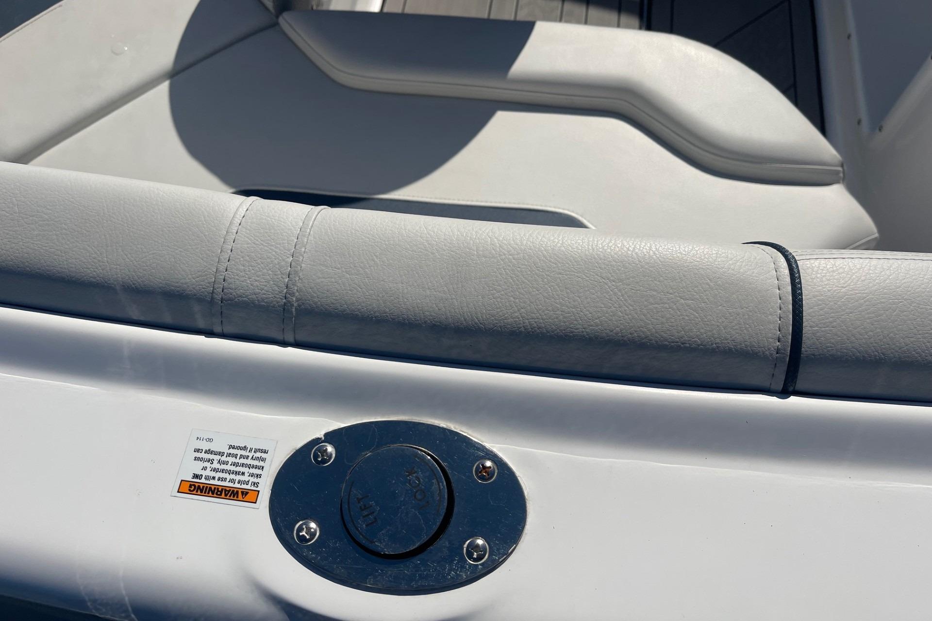 2023 Hurricane SunDeck 2400 OB boat interior with cushioned seating and metal fixture.