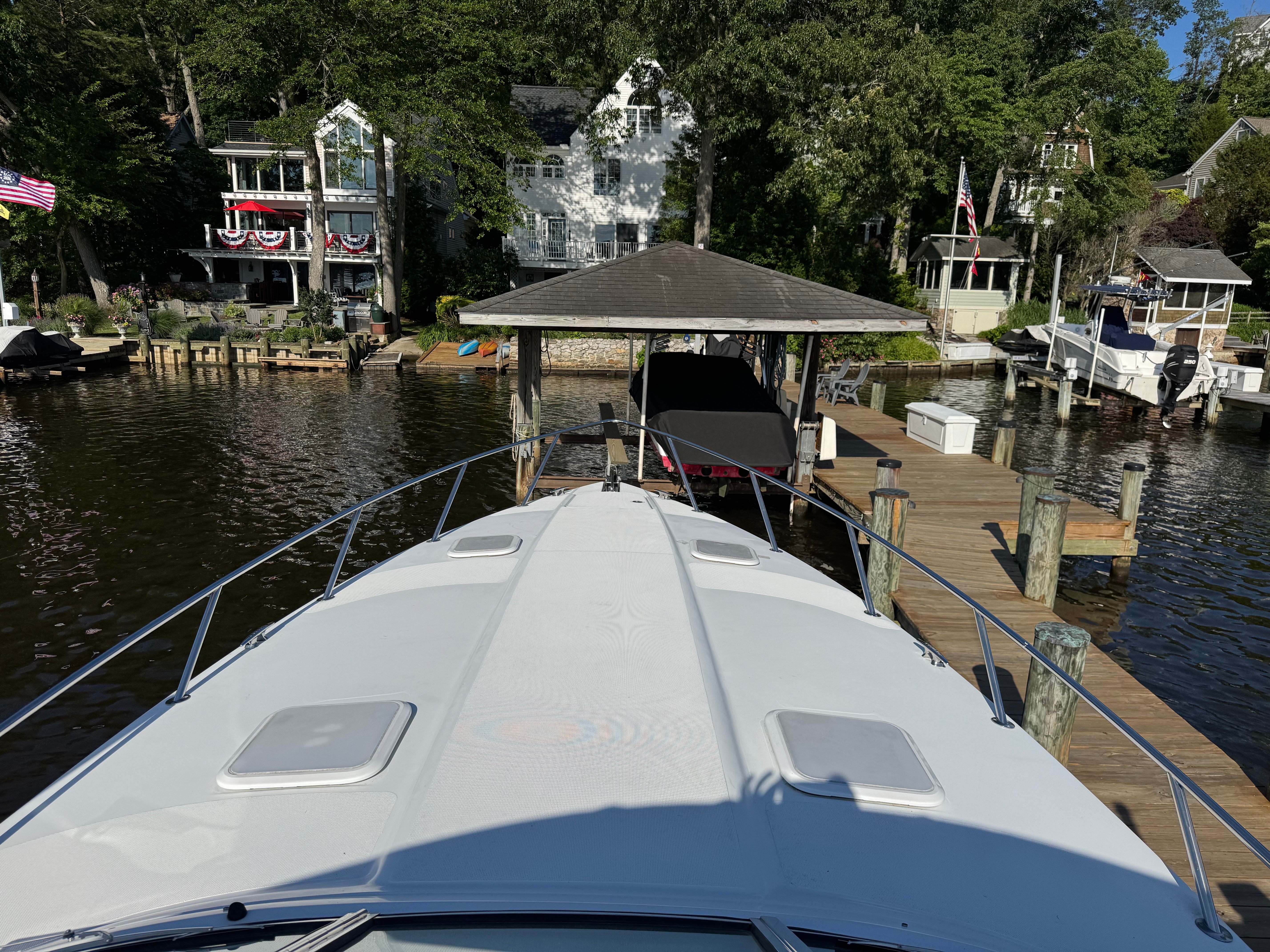 Boat at a dock with houses in the background, surrounded by trees.
