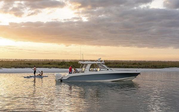 2024 Boston Whaler 380 Realm boat on calm water at sunset.