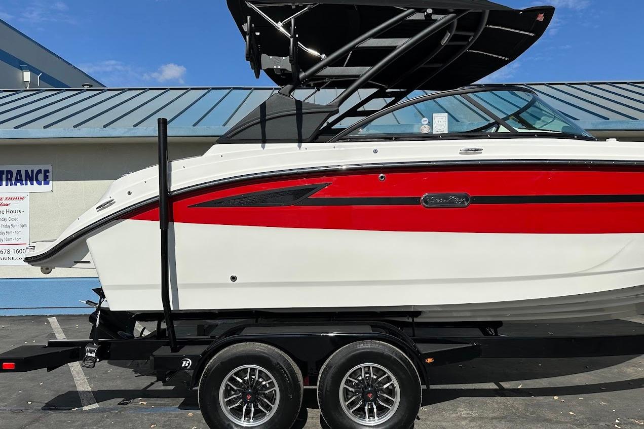 2026 Sea Ray SDX 230 Surf boat on trailer, red and white design, parked outdoors.