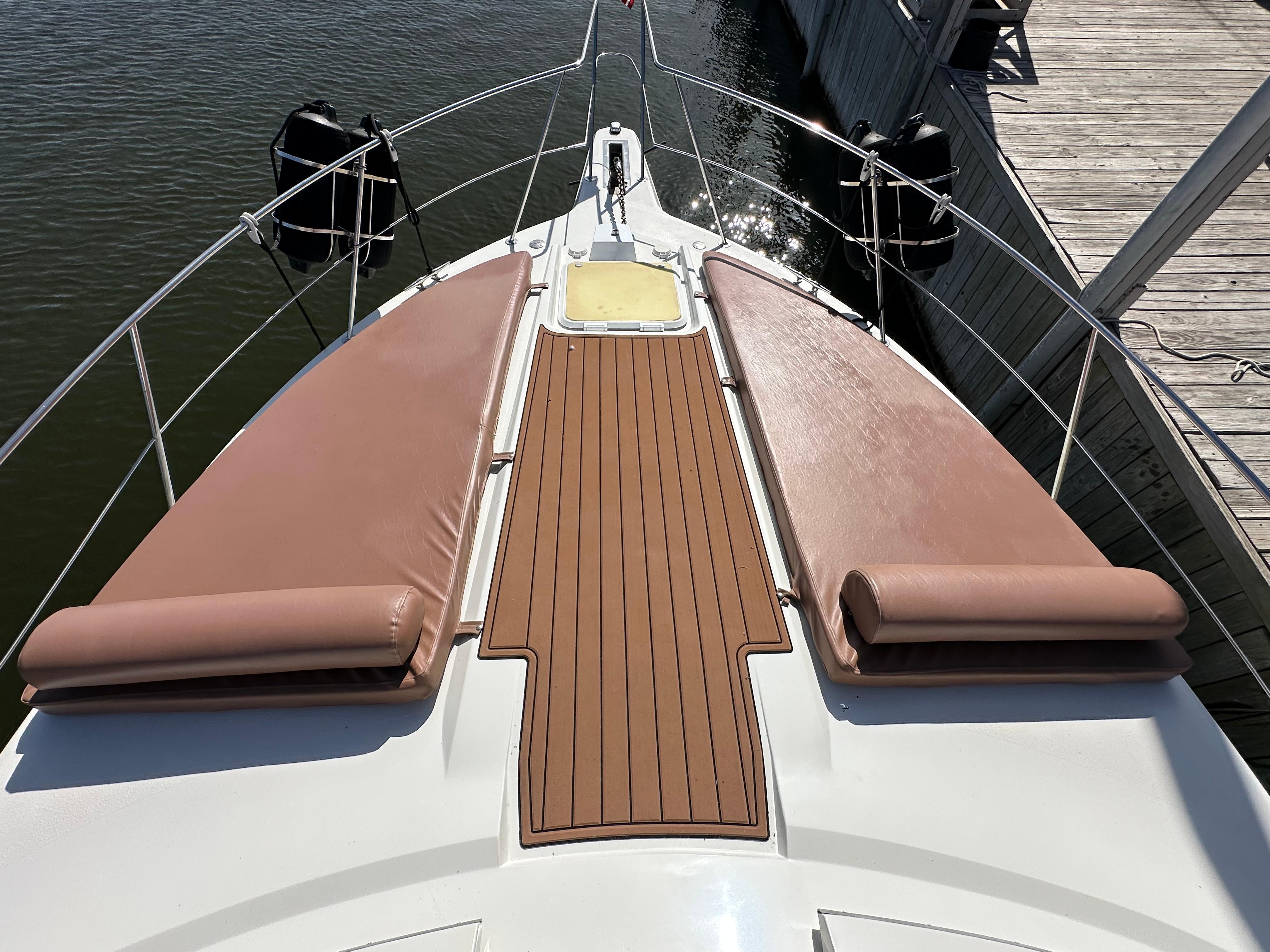 1996 Carver 38 Santego yacht bow with cushioned sun pads and wooden deck.