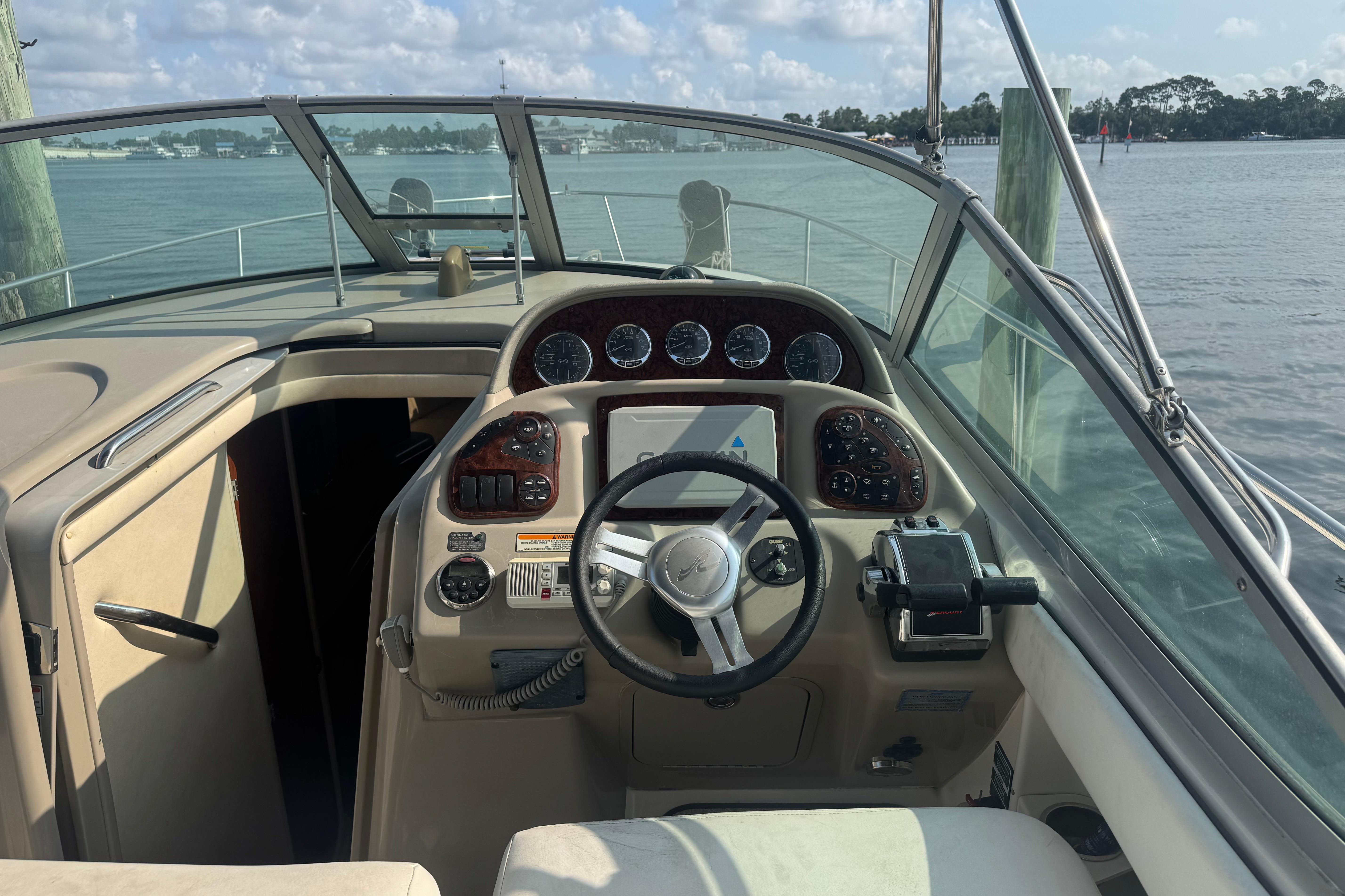 2006 Sea Ray 300 Sundancer helm with steering wheel, gauges, and water view.