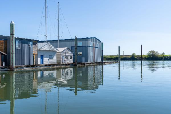 Boathouse on calm water, clear sky, Custom Larson Boathouse, 1985.