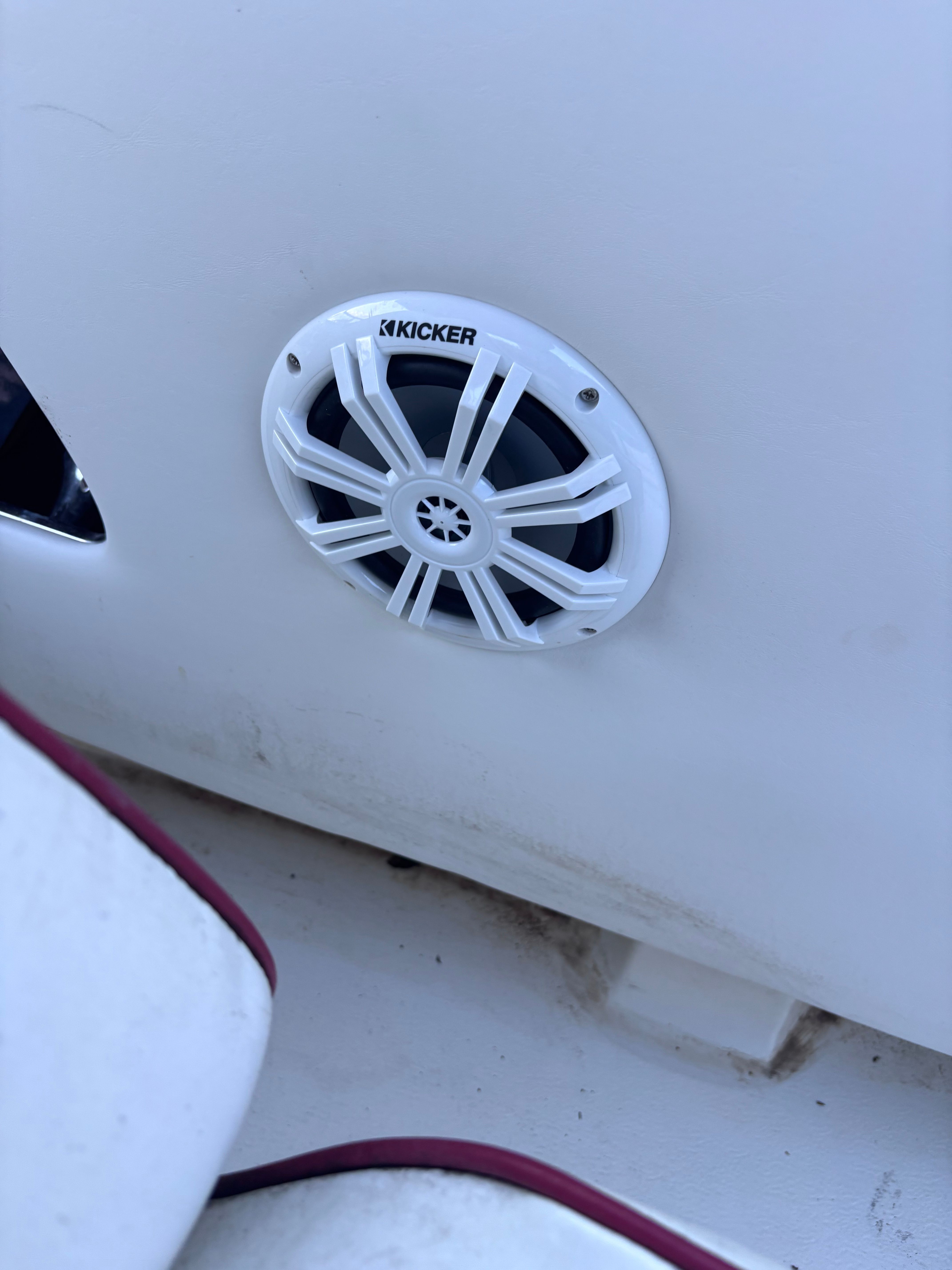 A speaker is mounted on the white interior wall of a boat.