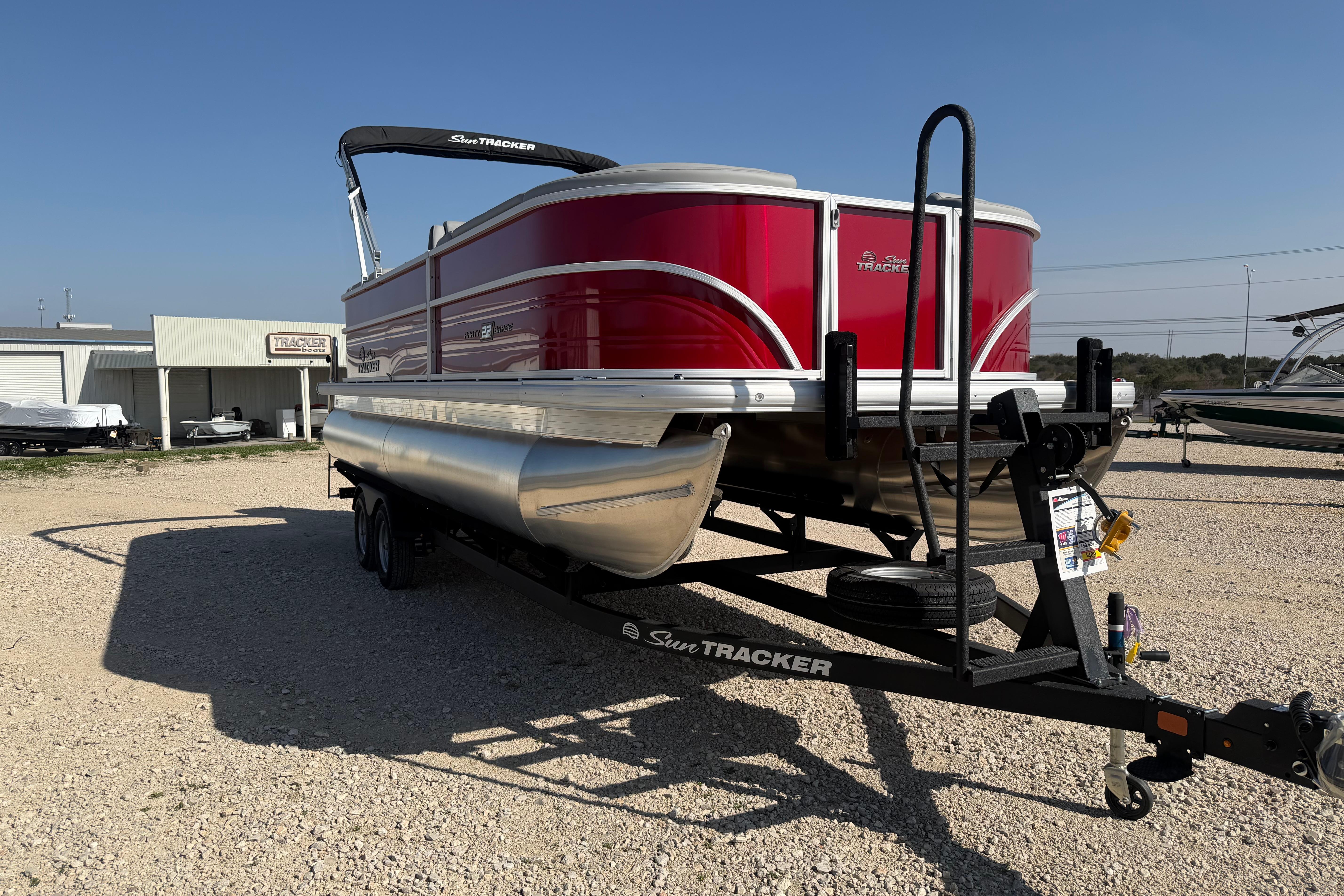 2026 Sun Tracker Party Barge 22 DLX pontoon boat on trailer, parked outdoors.